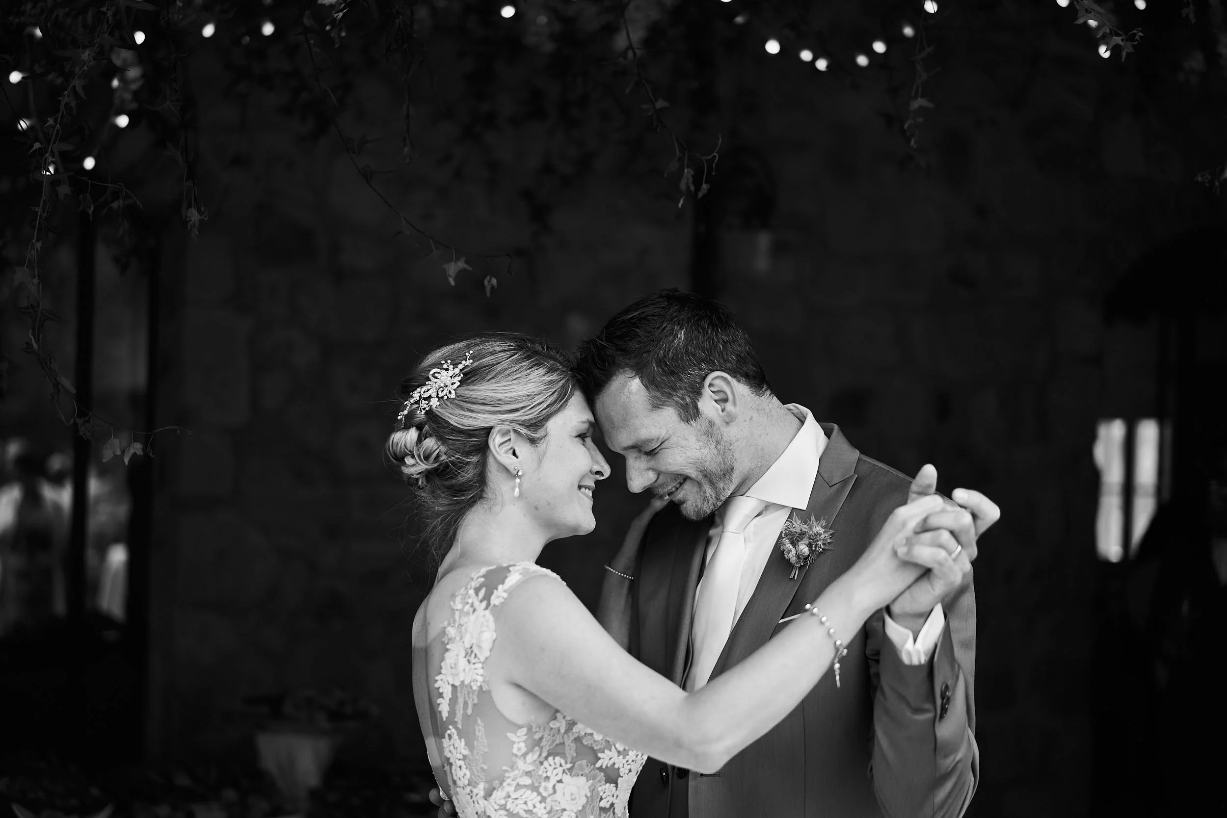 Bride and groom sharing their first dance, close and intimate, with soft bokeh lights behind them, during a destination wedding in Italy