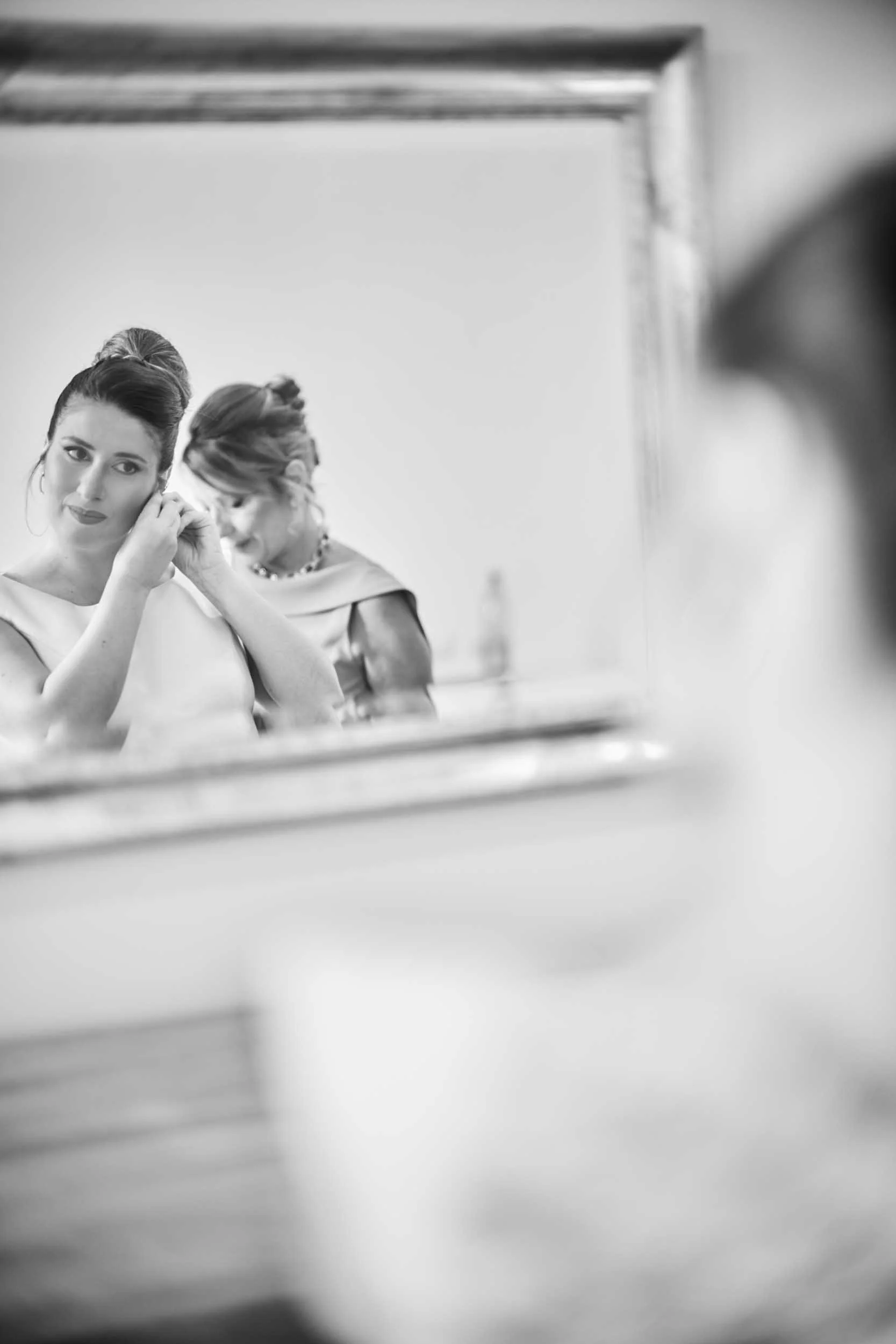 Black-and-white mirror reflection of the bride and her mother, emotional as they get ready