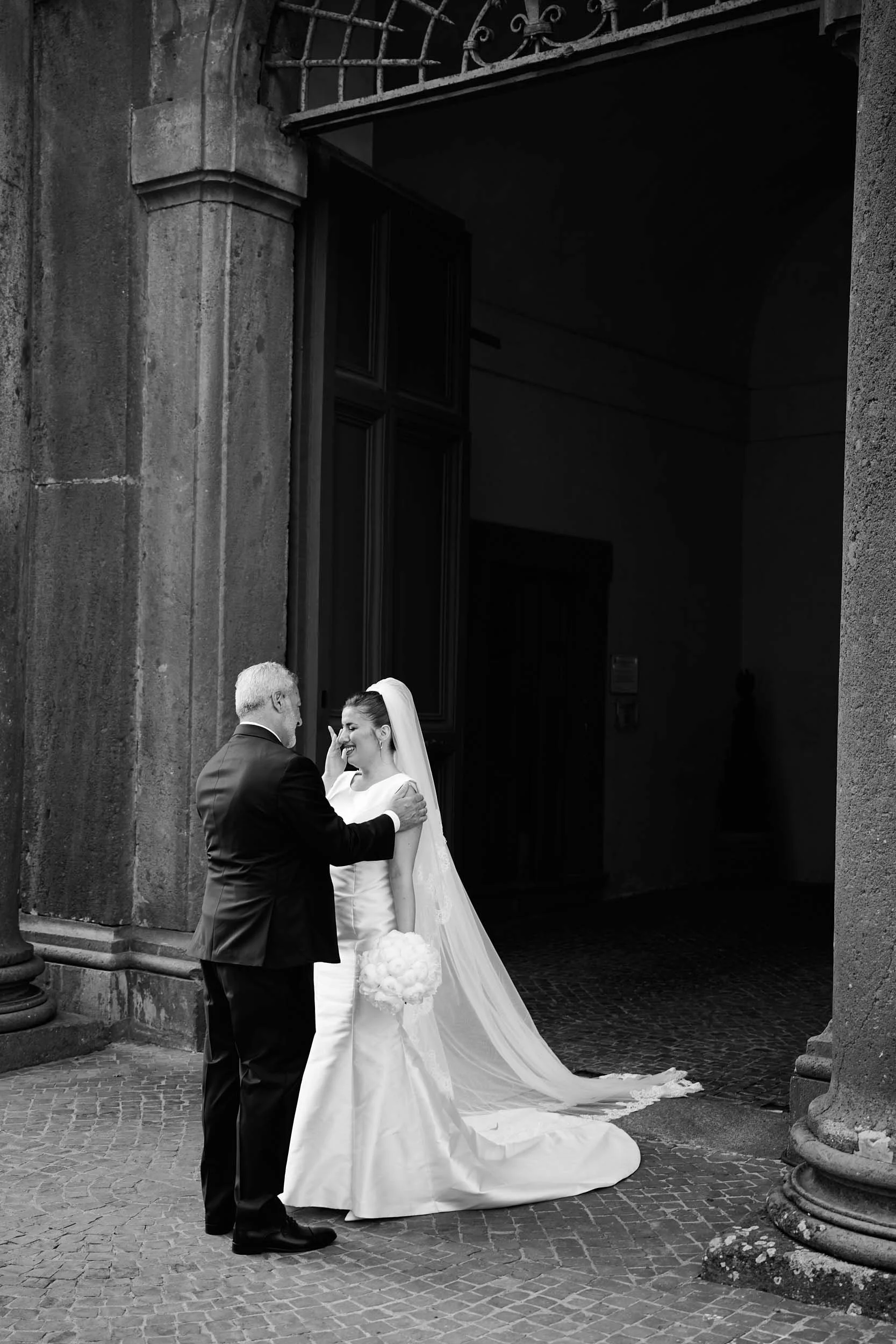 Bride and her father meet outside Villa Mondragone; emotional moment — black and white.