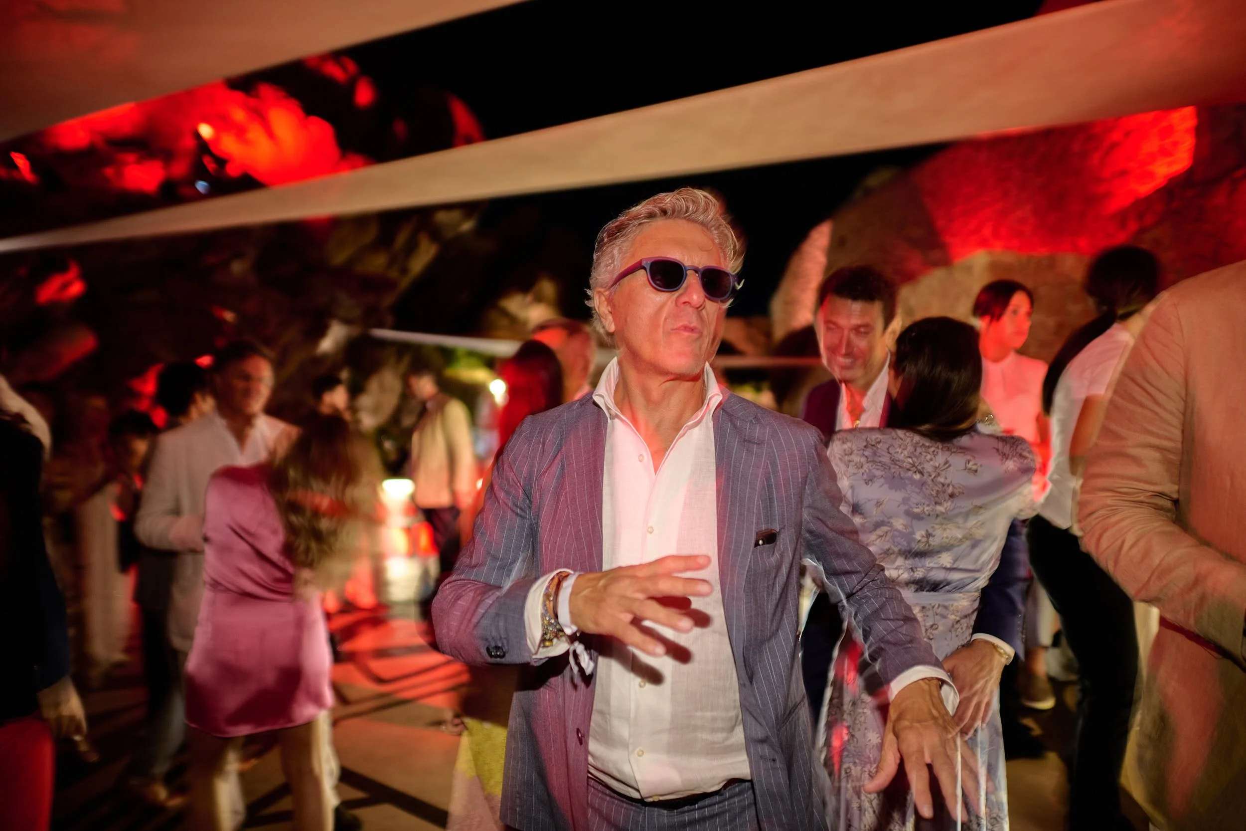 Guest dancing under dramatic red lighting during the night party at The Rock, Phi Beach, Costa Smeralda.