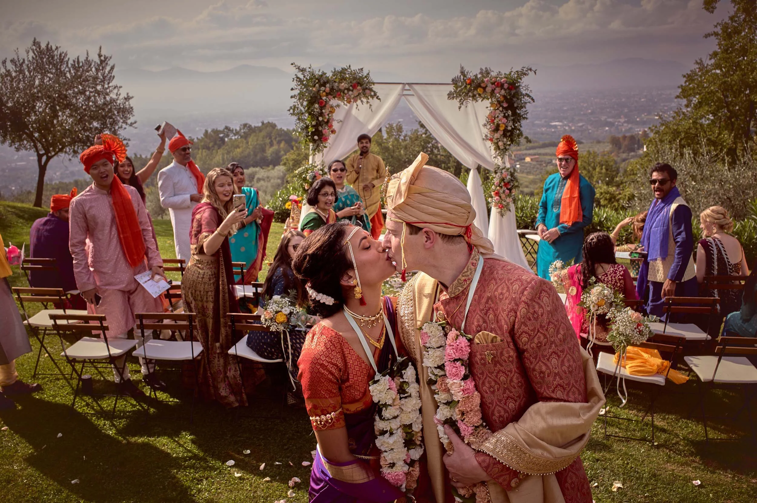 Bride and groom kiss surrounded by cheering guests — intimate destination wedding near Lucca, Tuscany