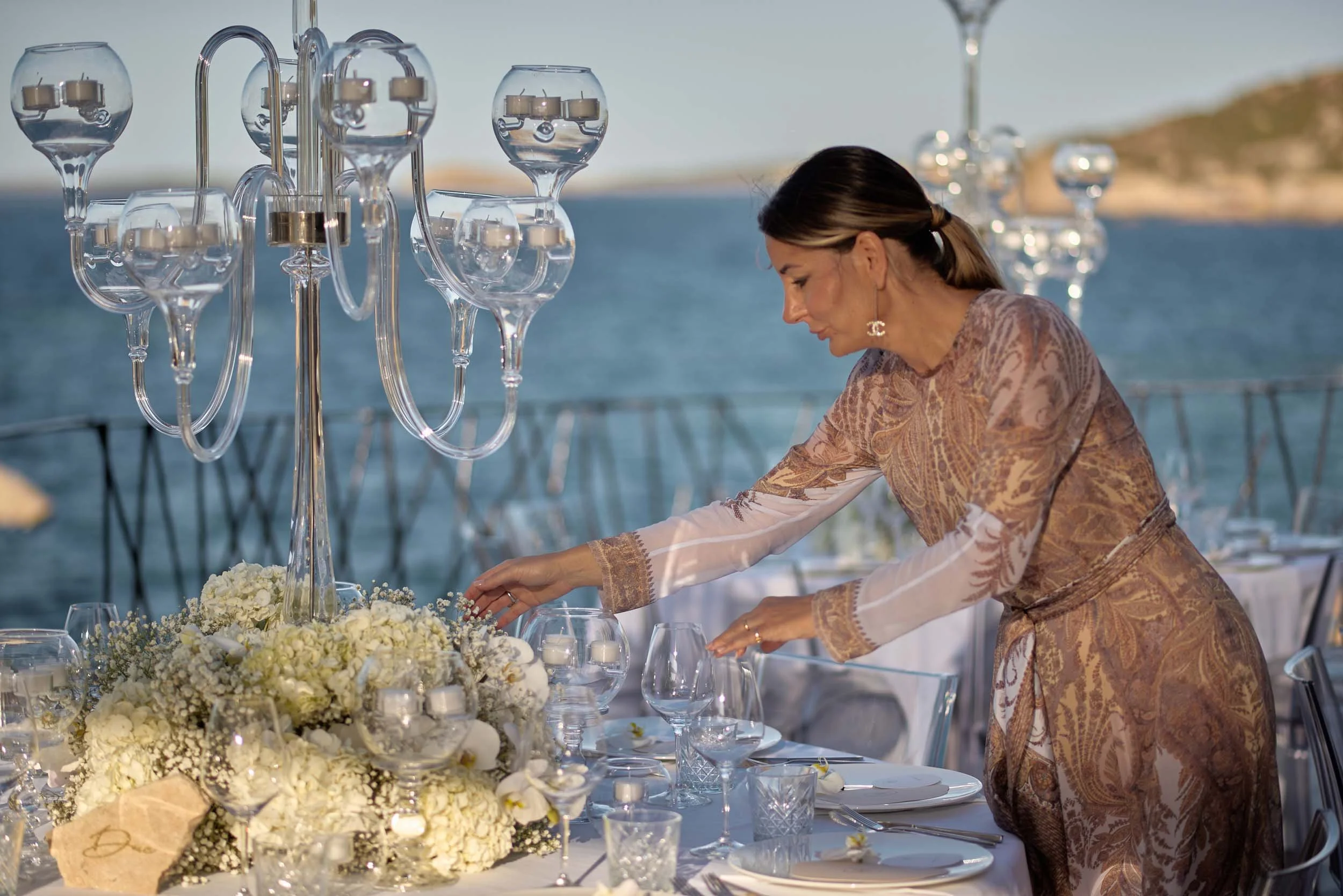 Wedding planner adjusting a seaside reception table — calm, discreet wedding coverage with breathing room.
