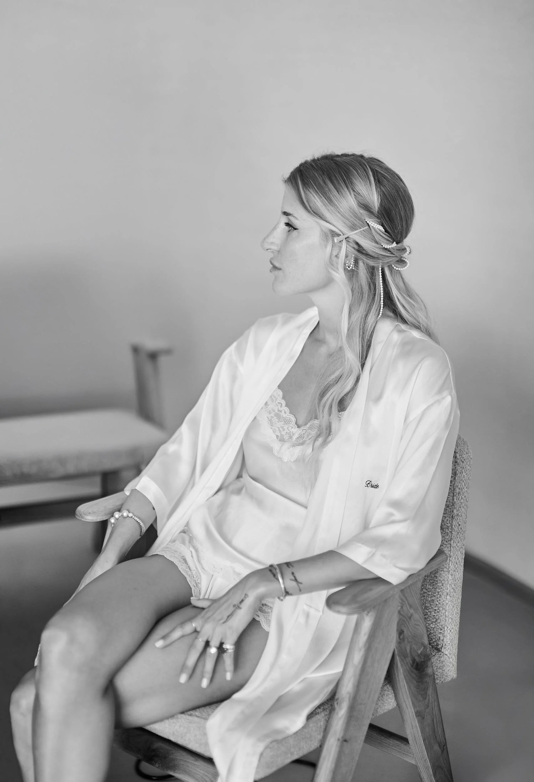 Bride in a robe, seated in profile during wedding preparations.