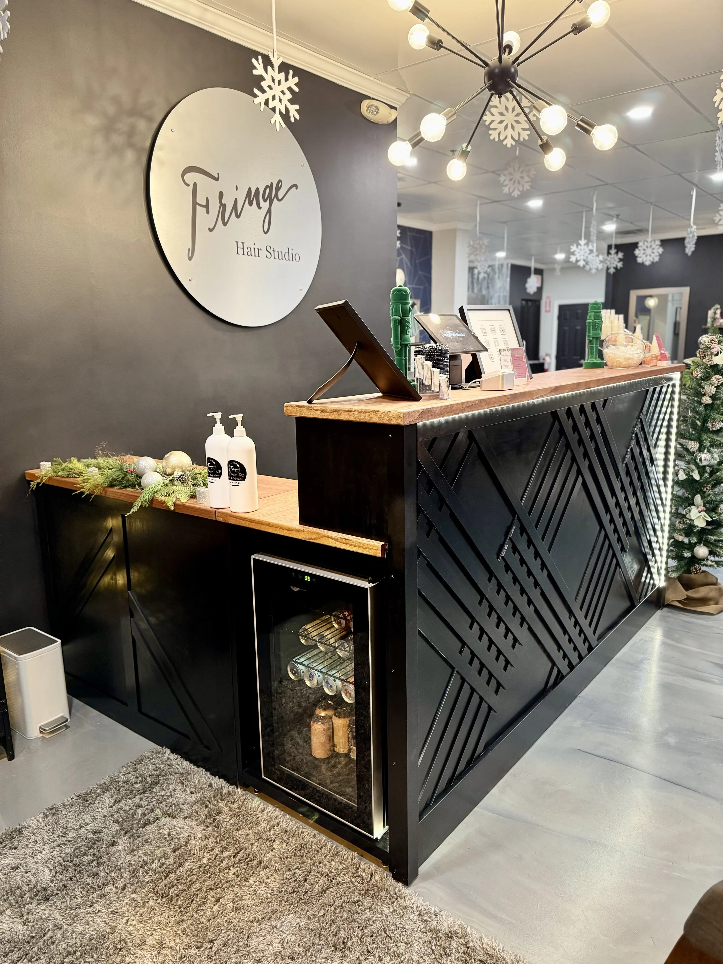 Reception area of Fringe Hair Studio decorated with holiday themed ornaments, a Christmas tree, and hanging snowflake decorations.