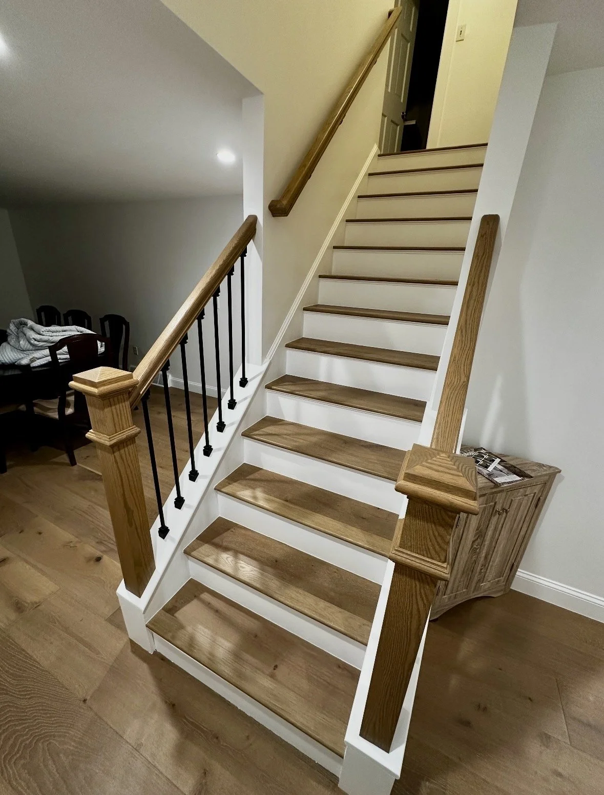 Wooden staircase with white risers and black metal balusters in a home interior.