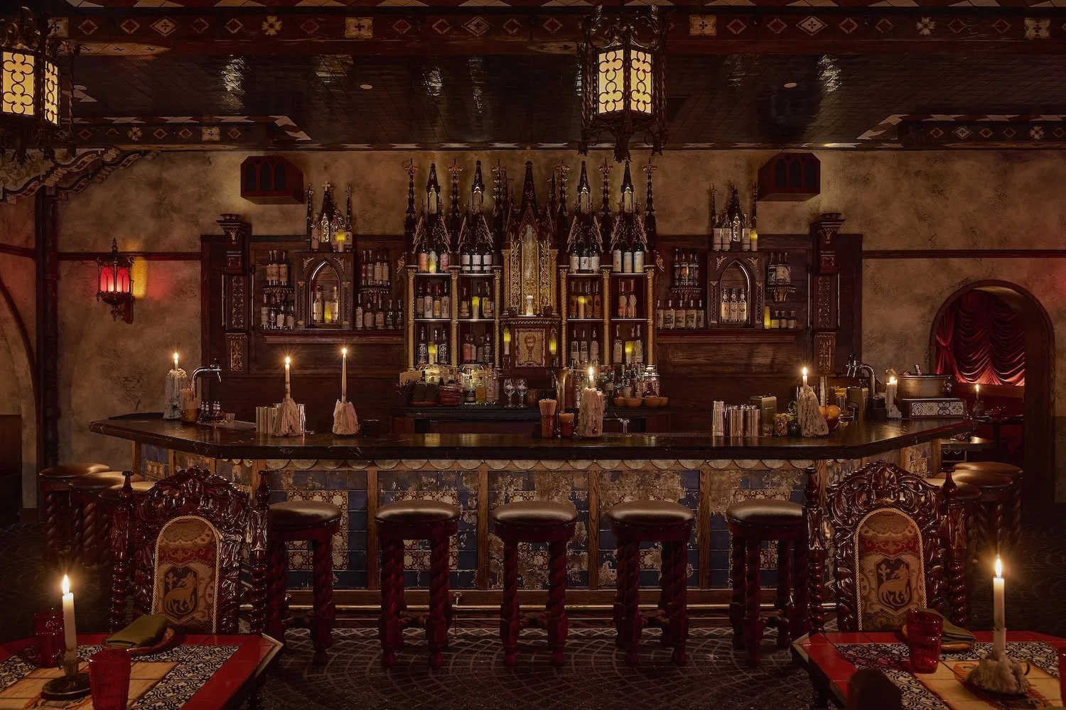 Dimly lit interior of Quixote at The Lafayette Hotel in San Diego, featuring stained glass, candlelight, and rich Oaxacan design details for a festive Cinco de Mayo dining experience.