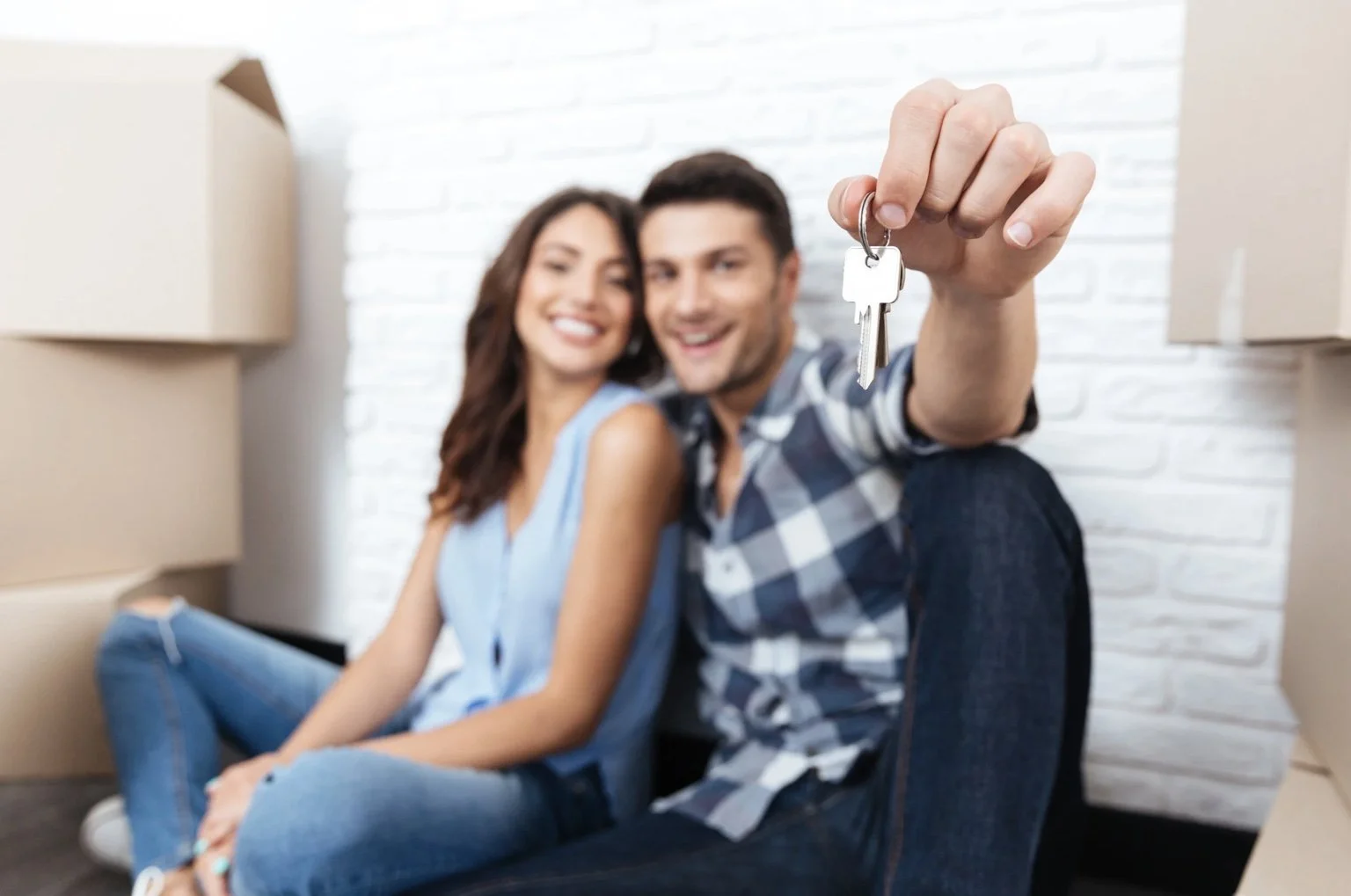 Couple holding house keys after moving into new home with professional removals service