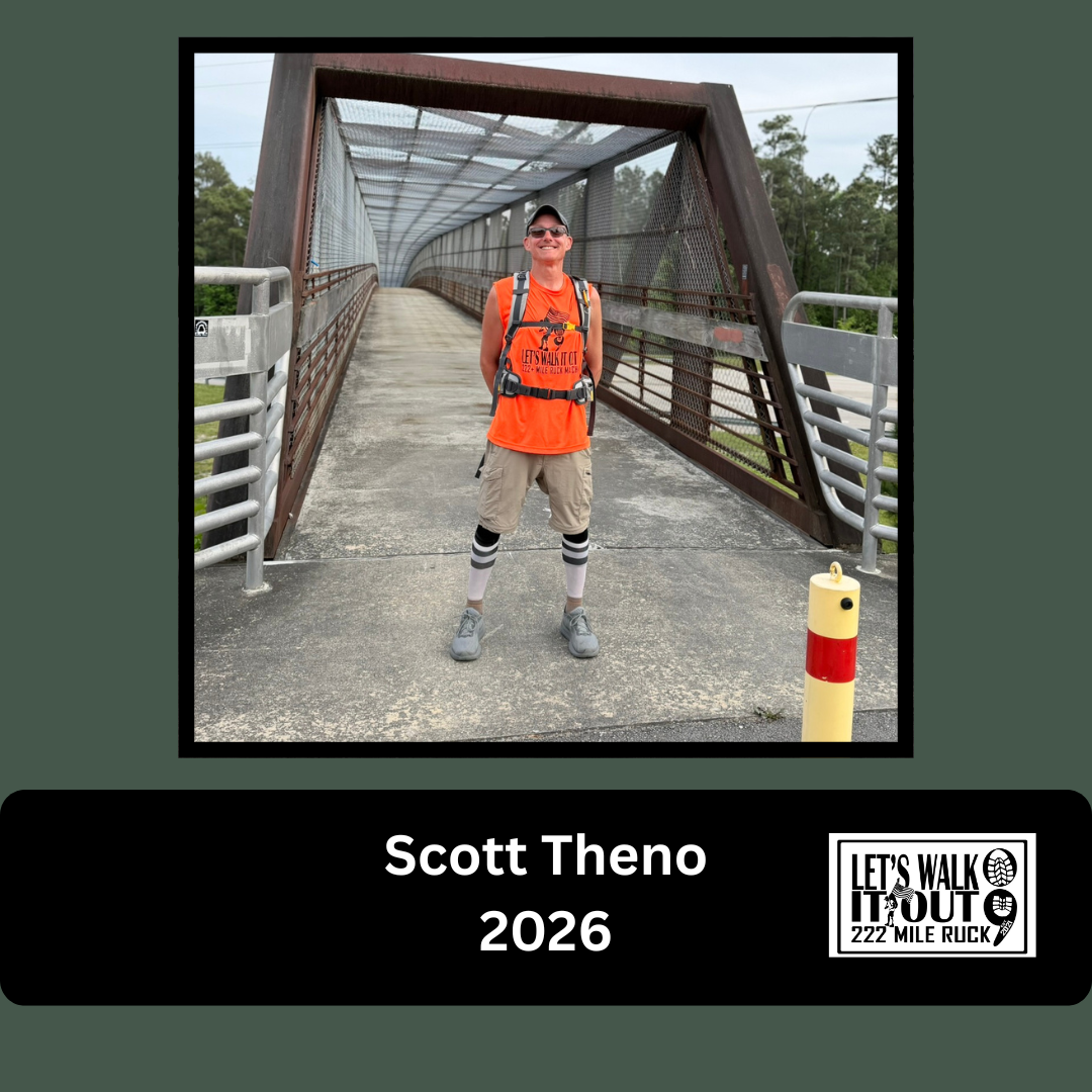 A man wearing a bright orange shirt, beige shorts, hiking gear, and striped knee-high socks stands on a bridge with a curved, enclosed walkway, smiling at the camera.