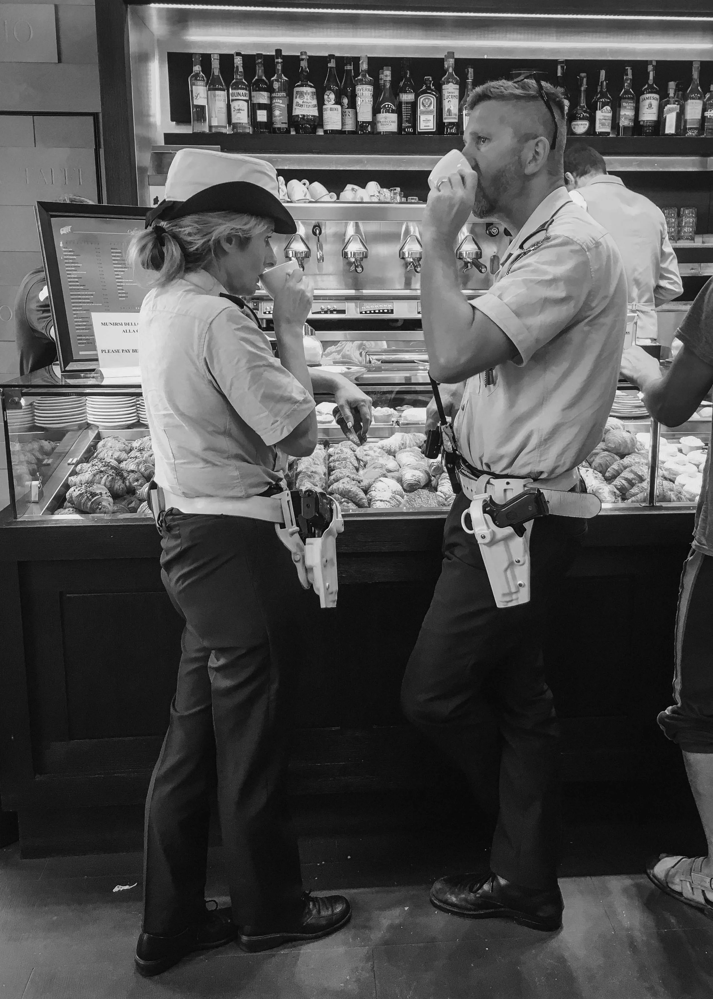 Two Carabinieri in uniform taking an espresso at an Italian bar, a candid black and white photograph of everyday life in Italy