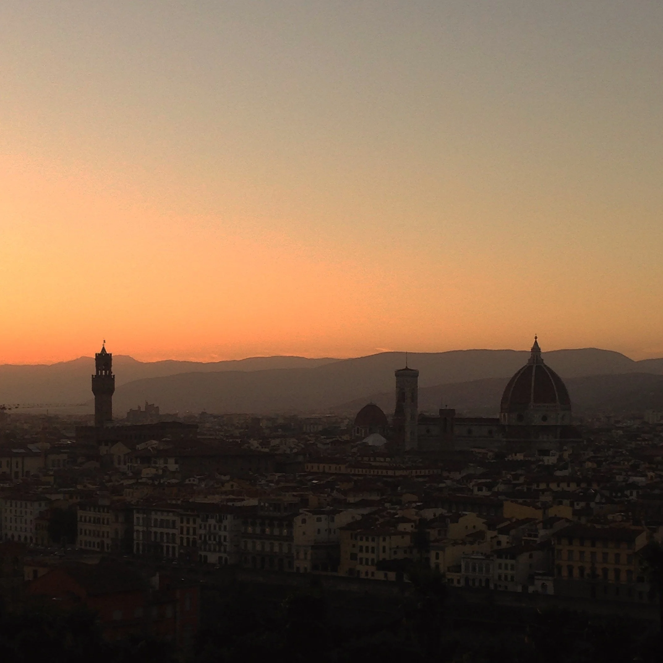 Sunset over Florence, Italy, with the Duomo and Torre di Arnolfo silhouetted against an amber sky