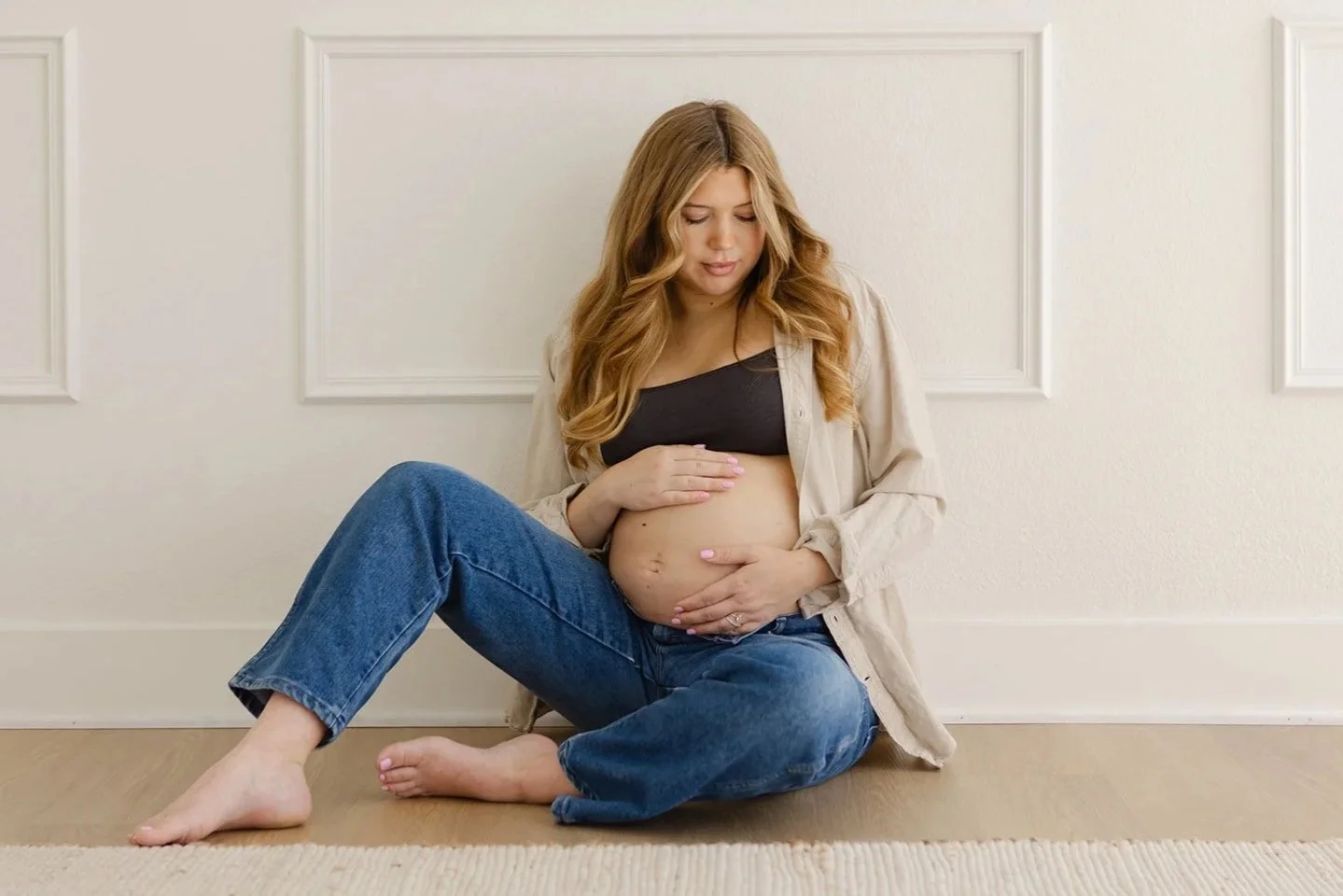 Mother-to-be seated on the floor during a natural light maternity photography session at The Arlen Studio in Westlake Village, photographed by Christine Harris.