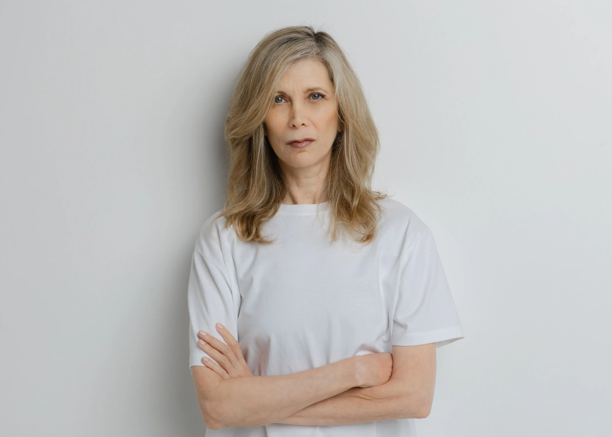 Portrait of costume designer Dayna Pink in a white t-shirt, arms crossed, photographed by Christine Harris