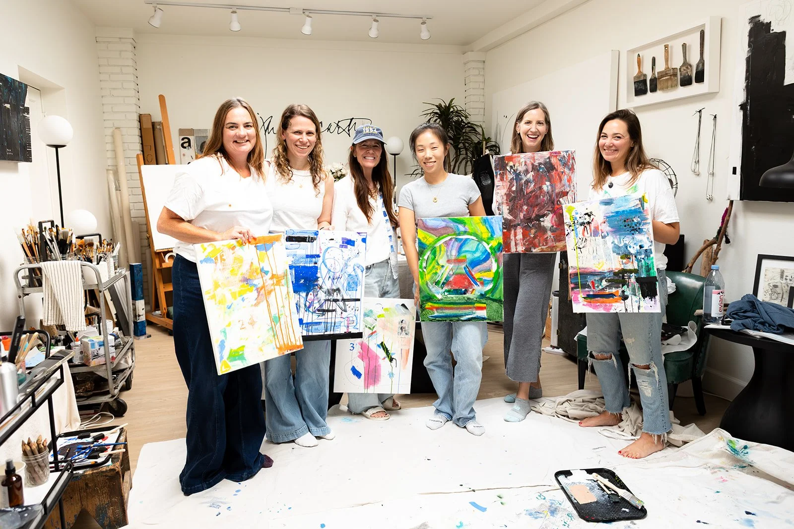Women holding their finished paintings at the end of a creative workshop in Jan McCarthy's studio, photographed by Christine Harris