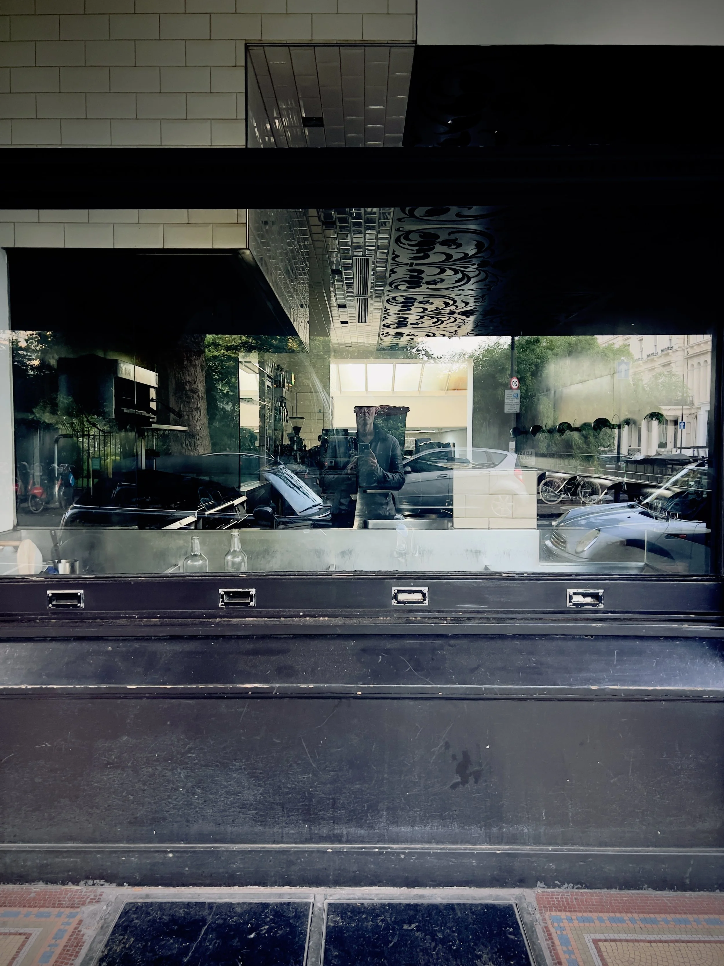 Reflection of man taking photo with smartphone in a window.