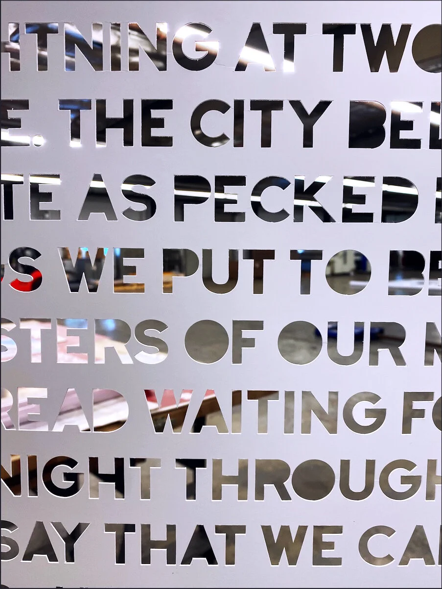 Close-up of a white surface with cut-out text revealing a blurred background.