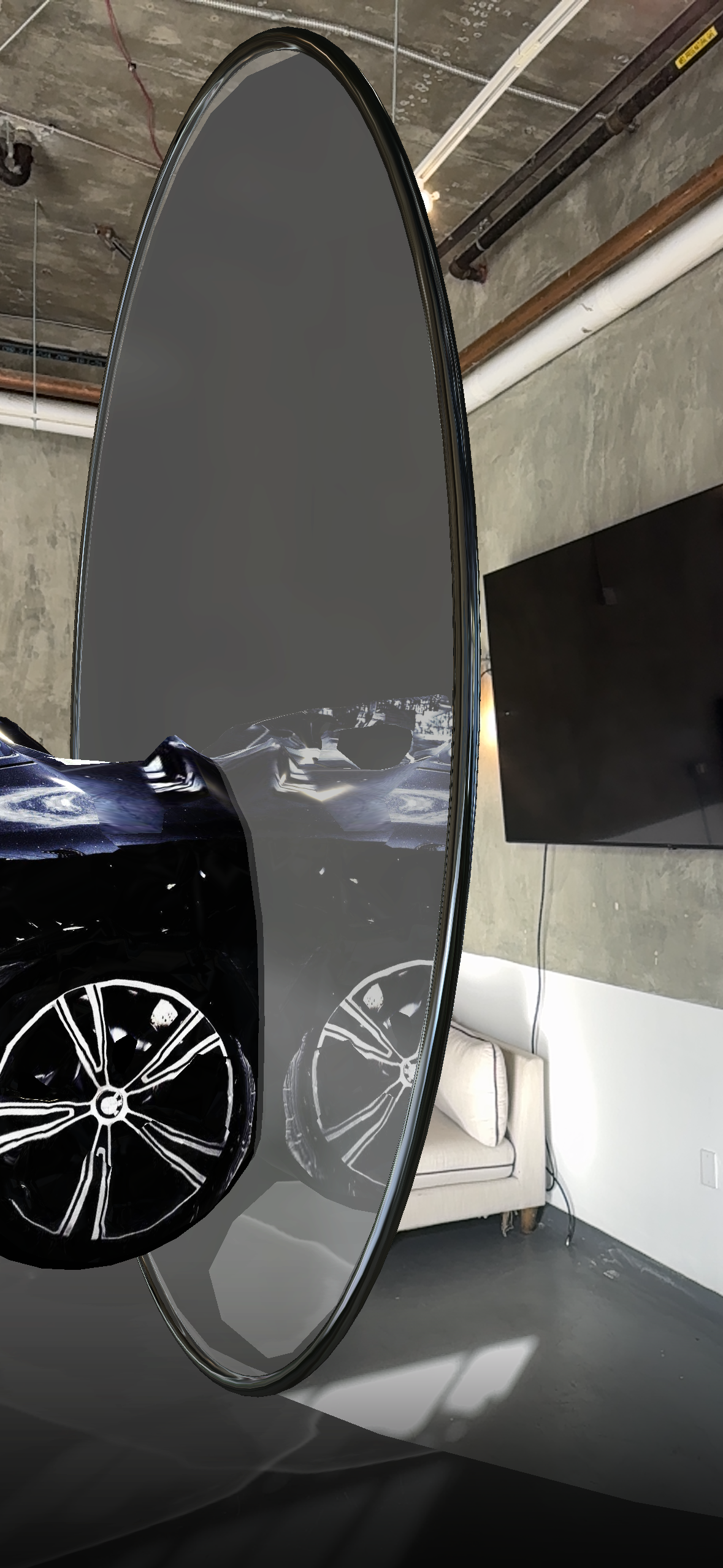 Large black oval object reflecting part of a car, situated indoors with a television and couch visible.