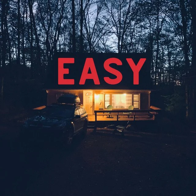 A house with a lit interior at dusk, with the word "EASY" in large red letters on its roof. Album artwork for the song "Easy" by Sean Kiely