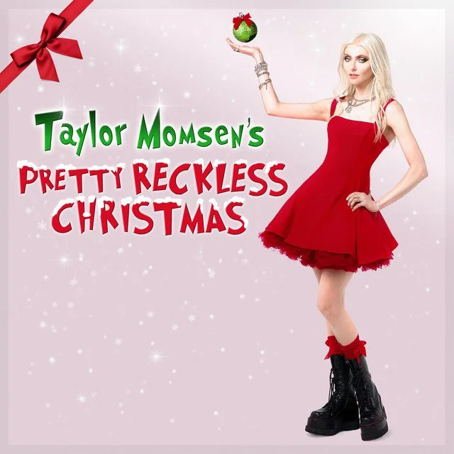 Album artwork for 'Taylor Momsen's Pretty Reckless Christmas' by The Pretty Reckless, featuring a woman in a red dress, black combat boots, and holding a Christmas ornament against a pink background with snowflakes and a red bow in the corner.