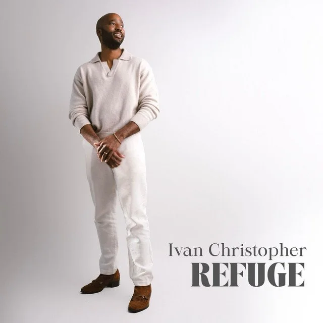 Album artwork for the "Refuge" by Ivan Christopher, featuring a man with a beard wearing a beige sweater and white pants standing against a plain white background, looking to the side with a smile. Text reads 'Ivan Christopher REFUGE'.