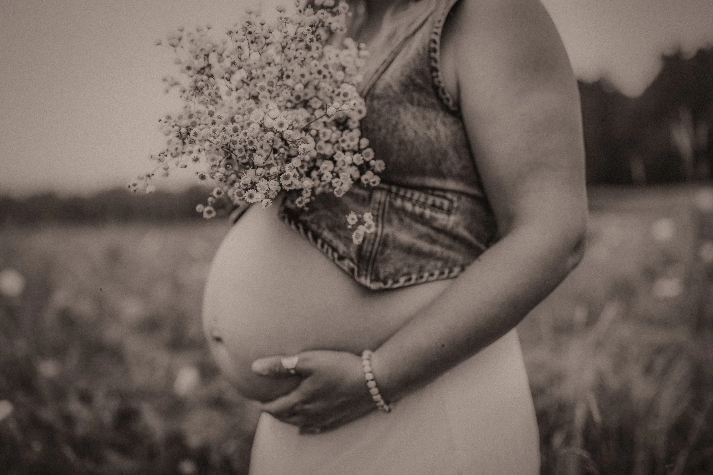 maternity client in vermont in a field holding flowers with her baby belly