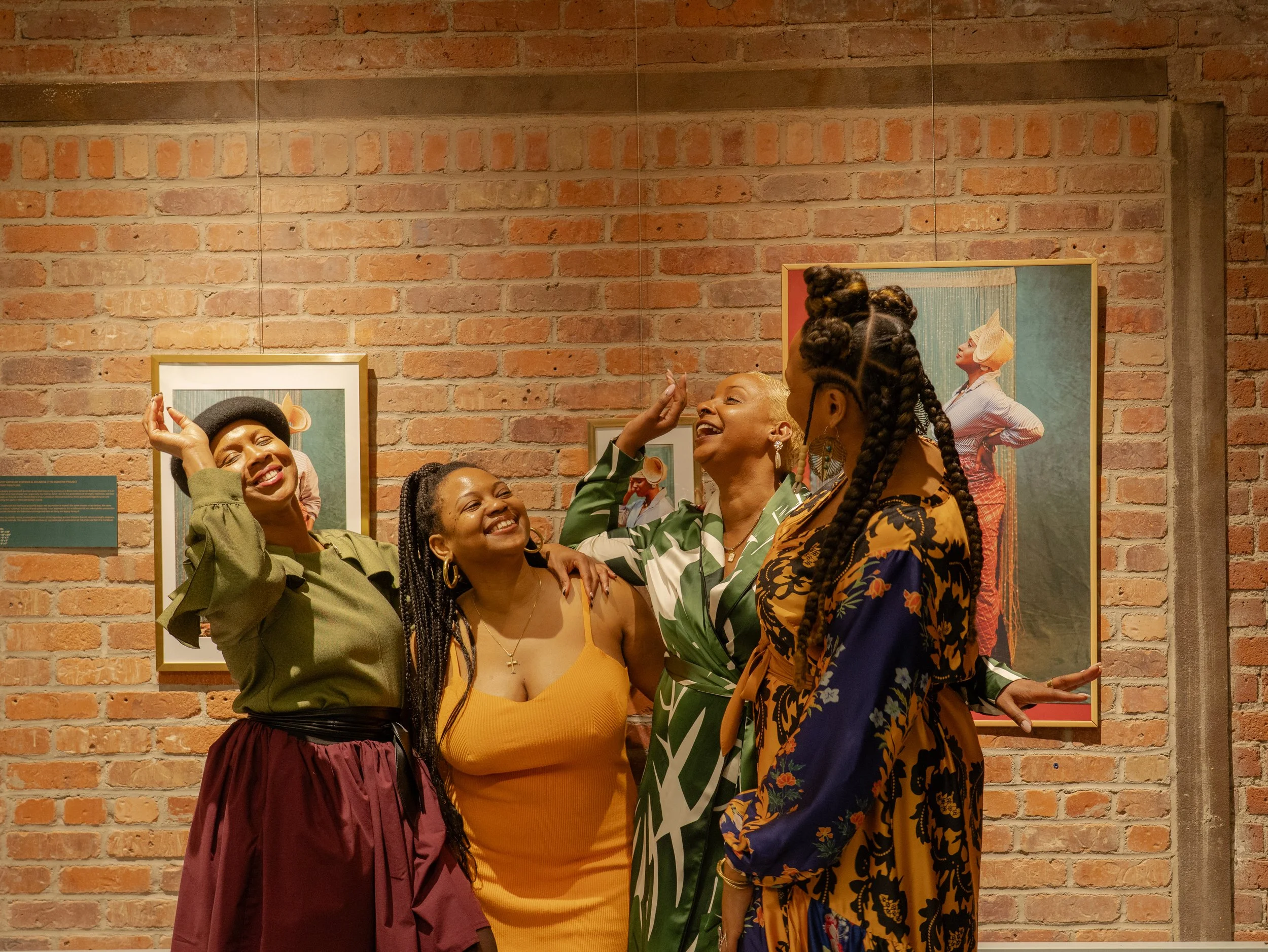 Steffie and friends pose joyfully in front of Steffie's portraits at the CEI