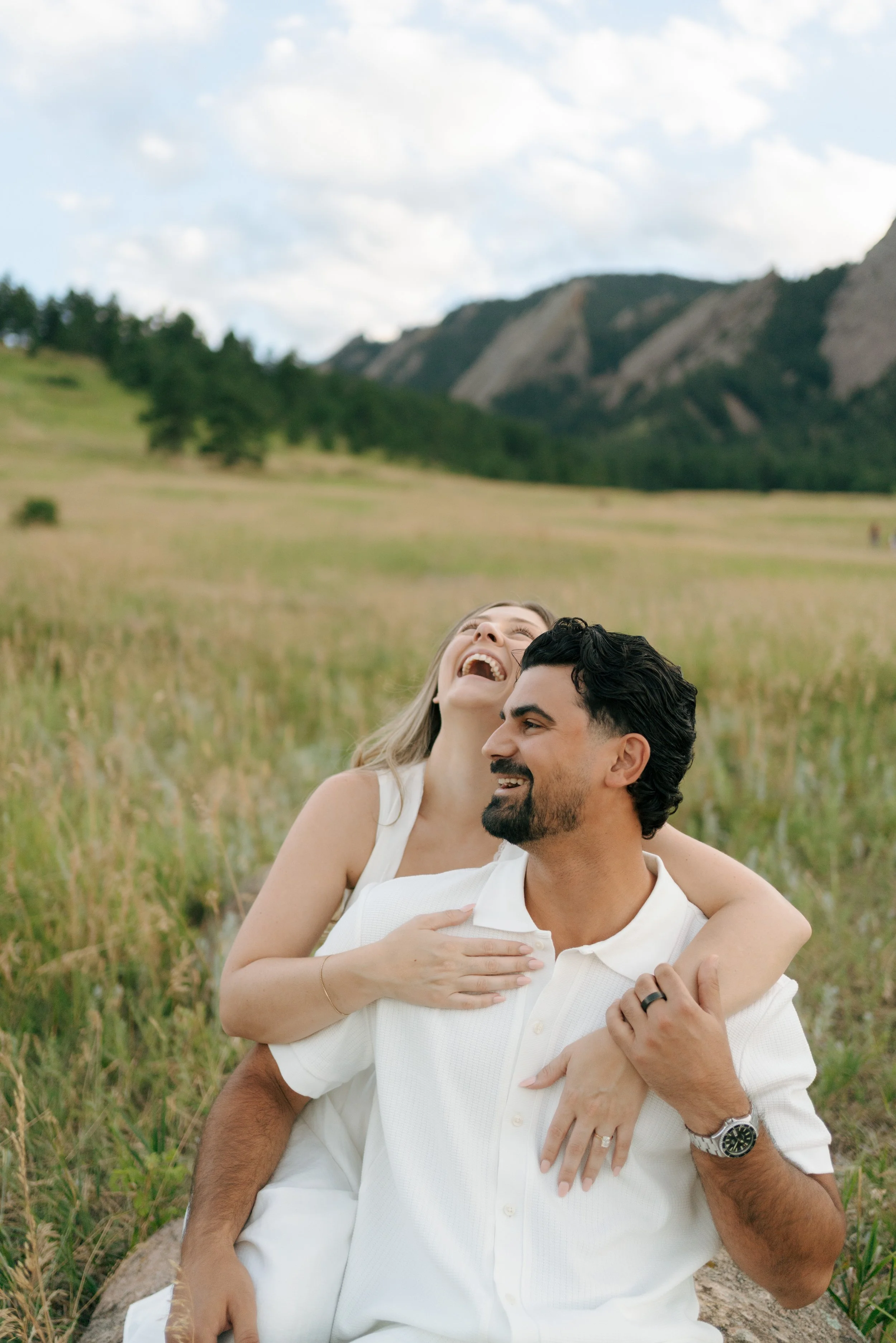 a woman laughing as she hangs on to a man from behind during Chautauqua Park Engagement Photos