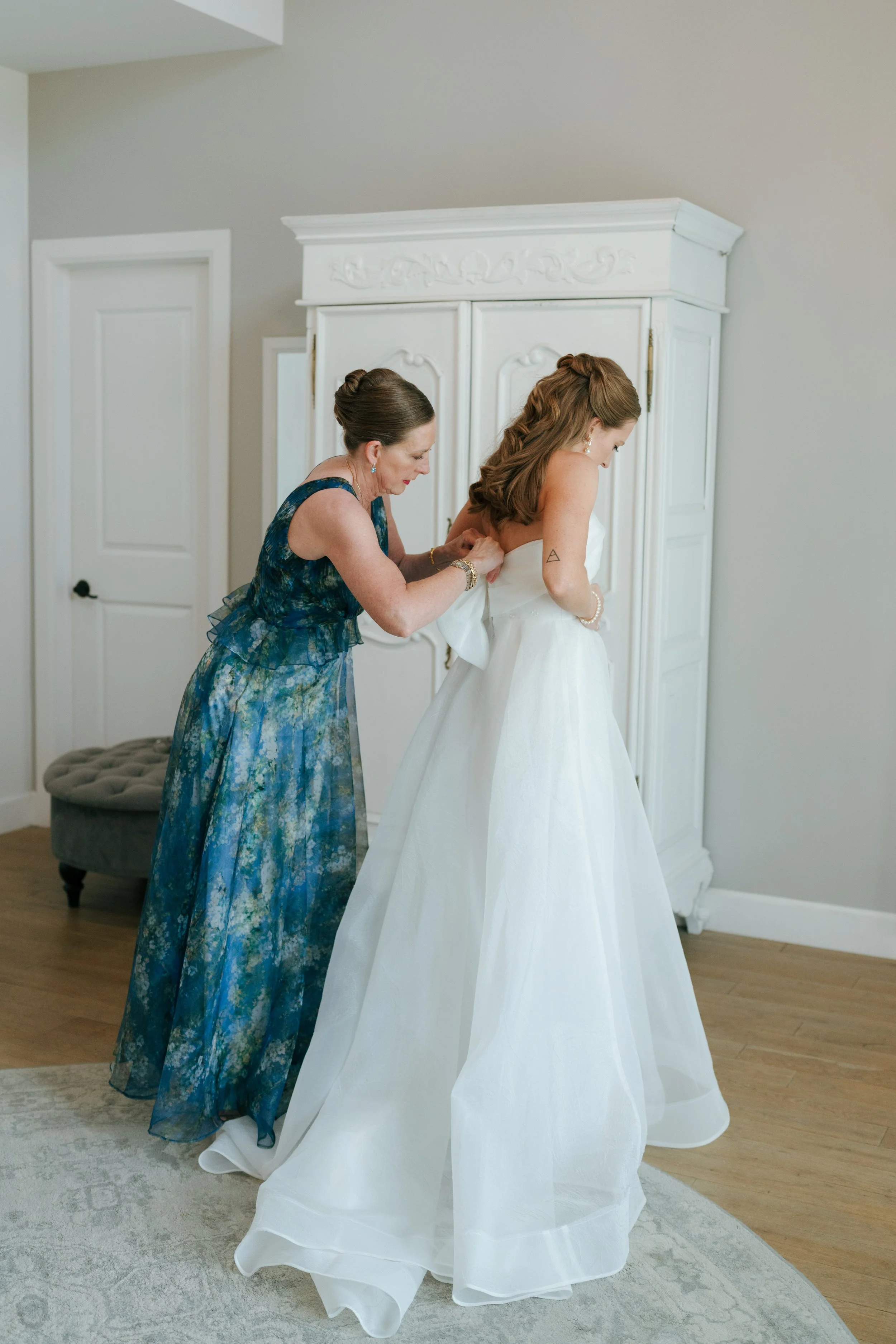 bride's mom helping her zip her dress at The Barn at Raccoon Creek
