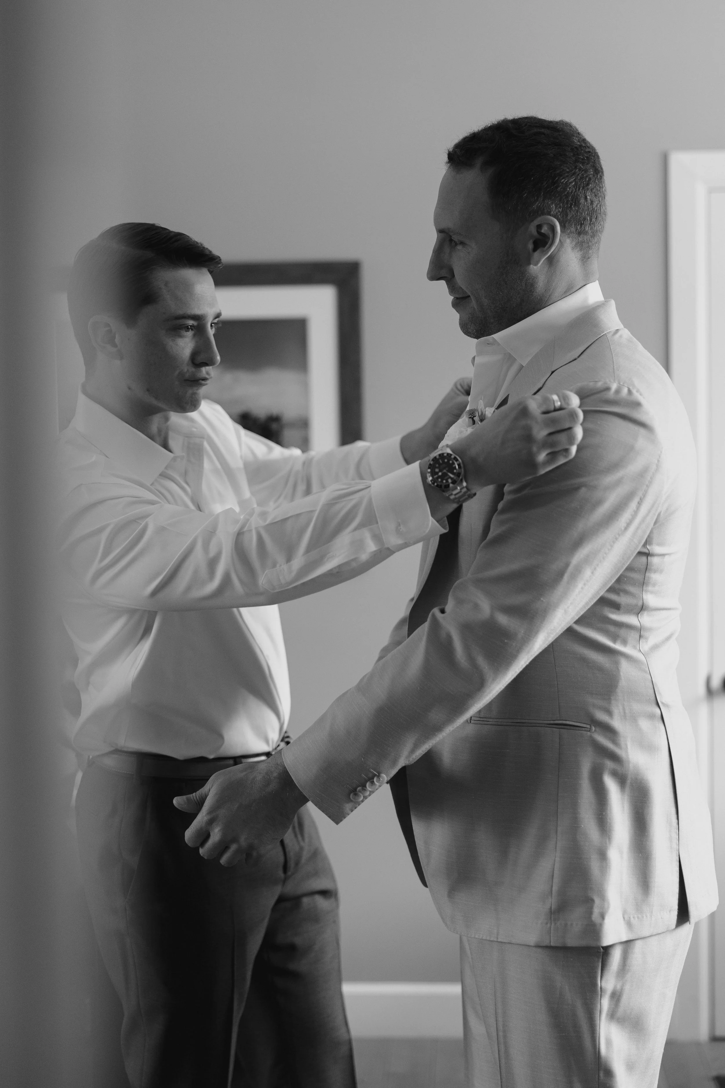 someone helping the groom with his suit 