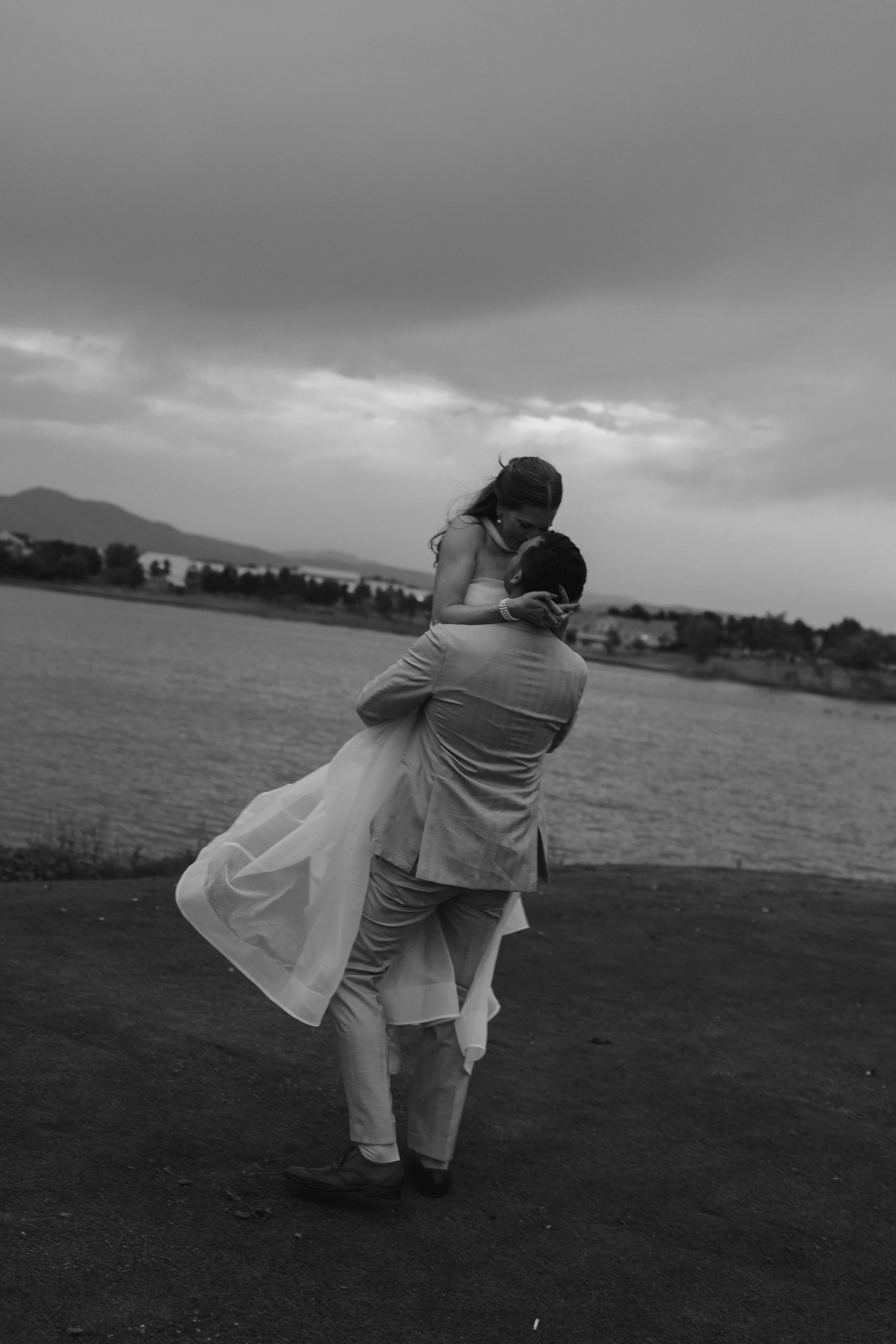 groom picking bride up by the lake 