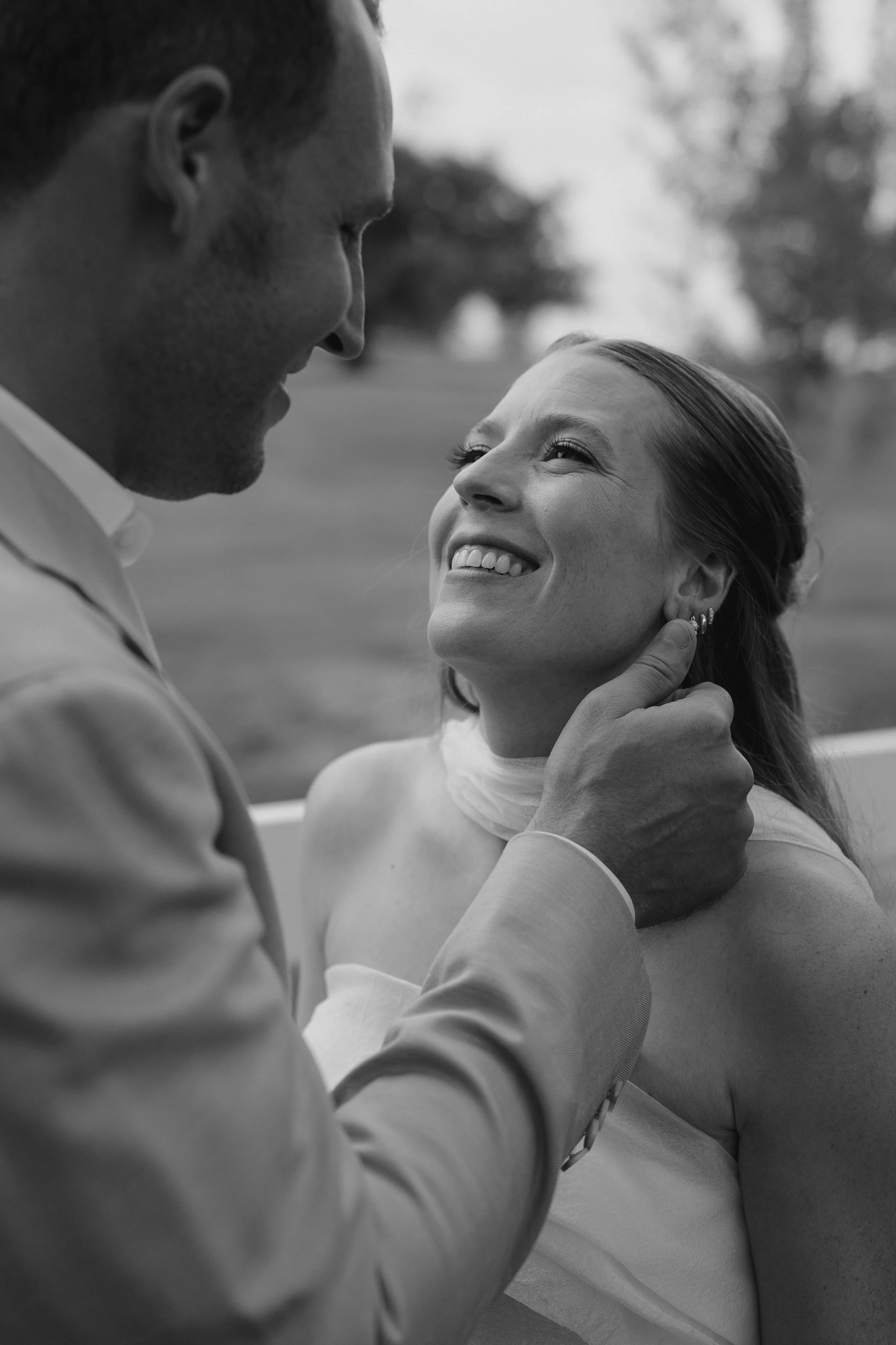 bride looking at the groom as he strokes her face 