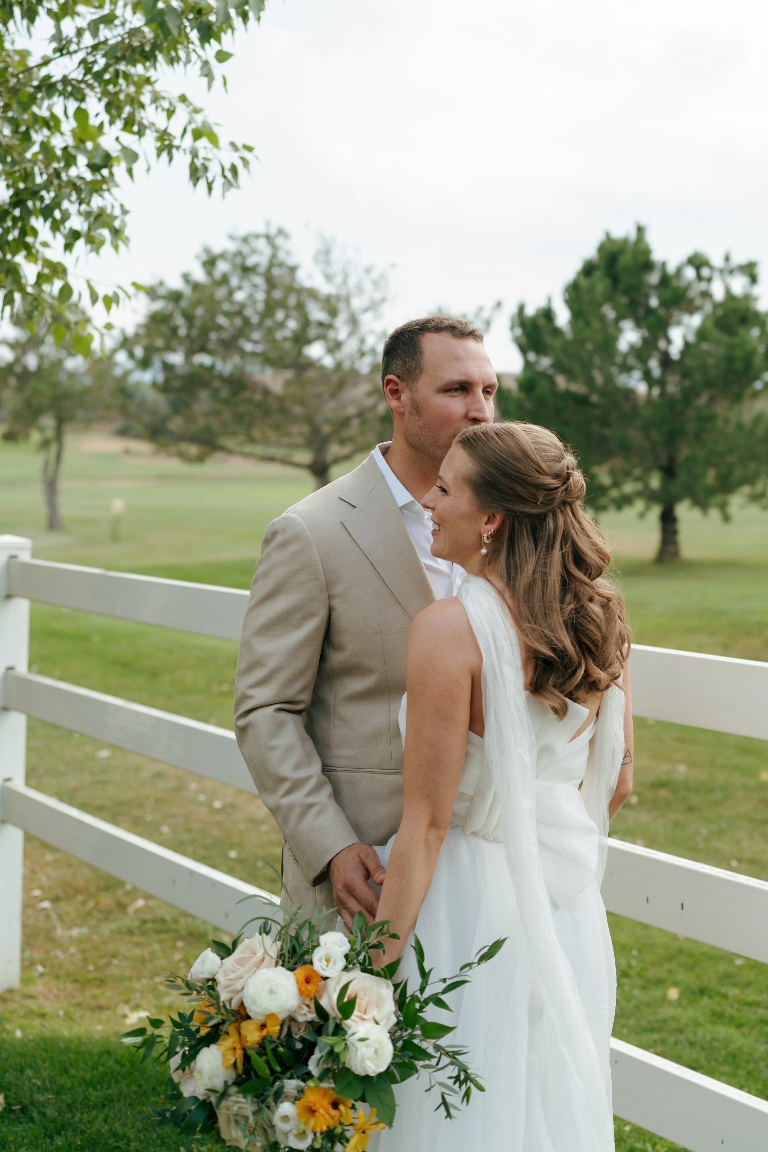 bride and groom portrait by a white fence