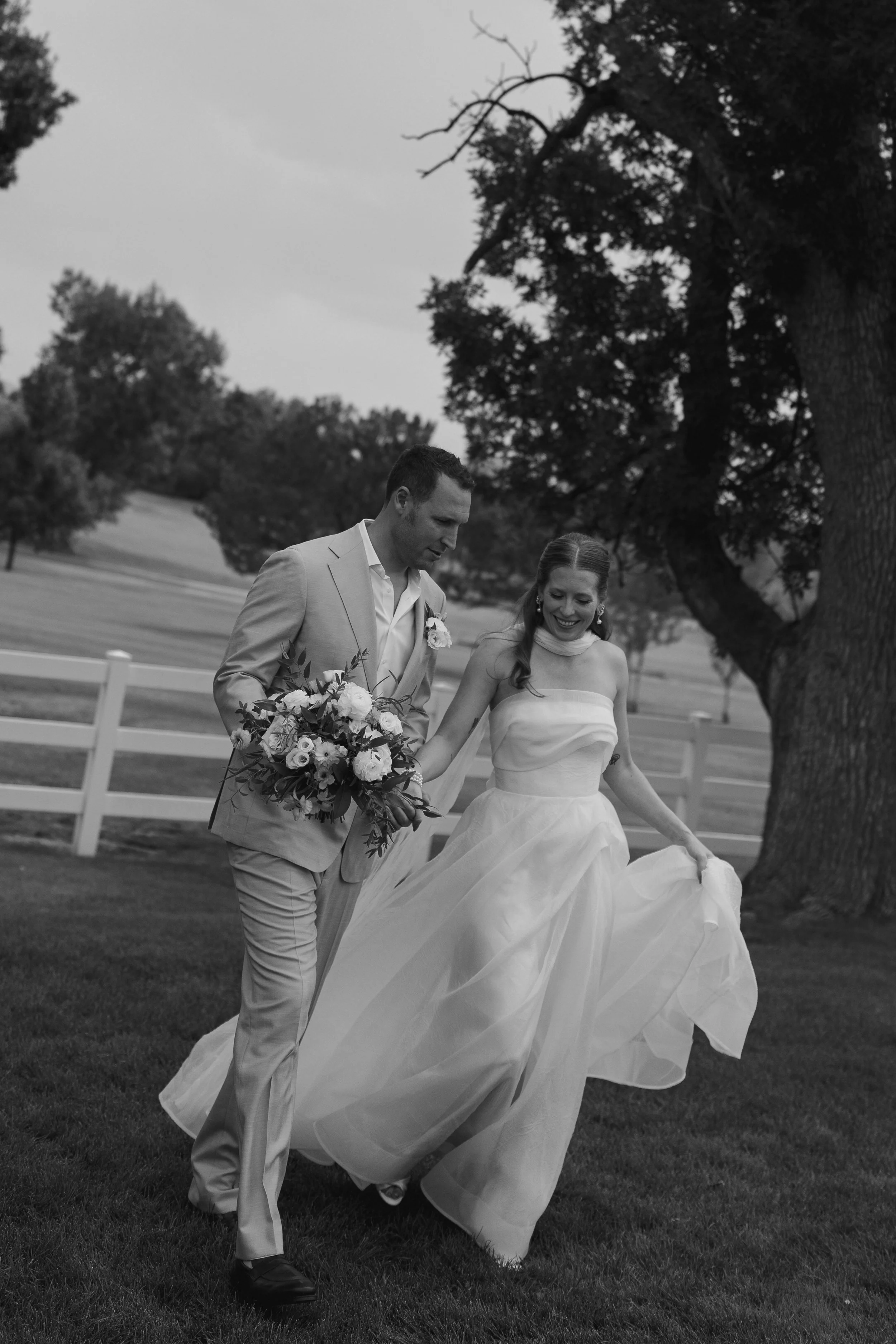 bride and groom walking through the grass