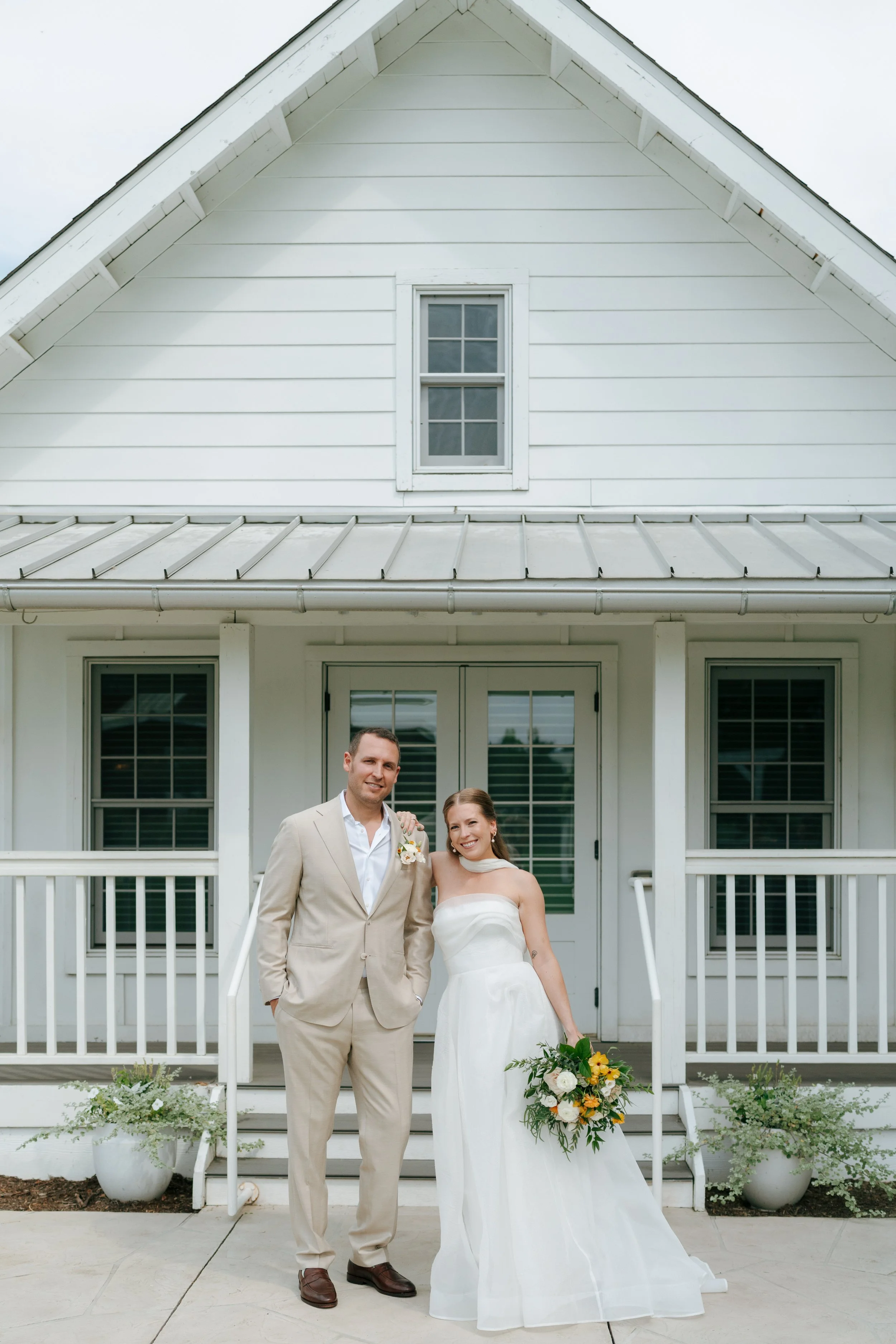 the wedding couple standing in front of the bridal cottage at The Barn at Raccoon Creek