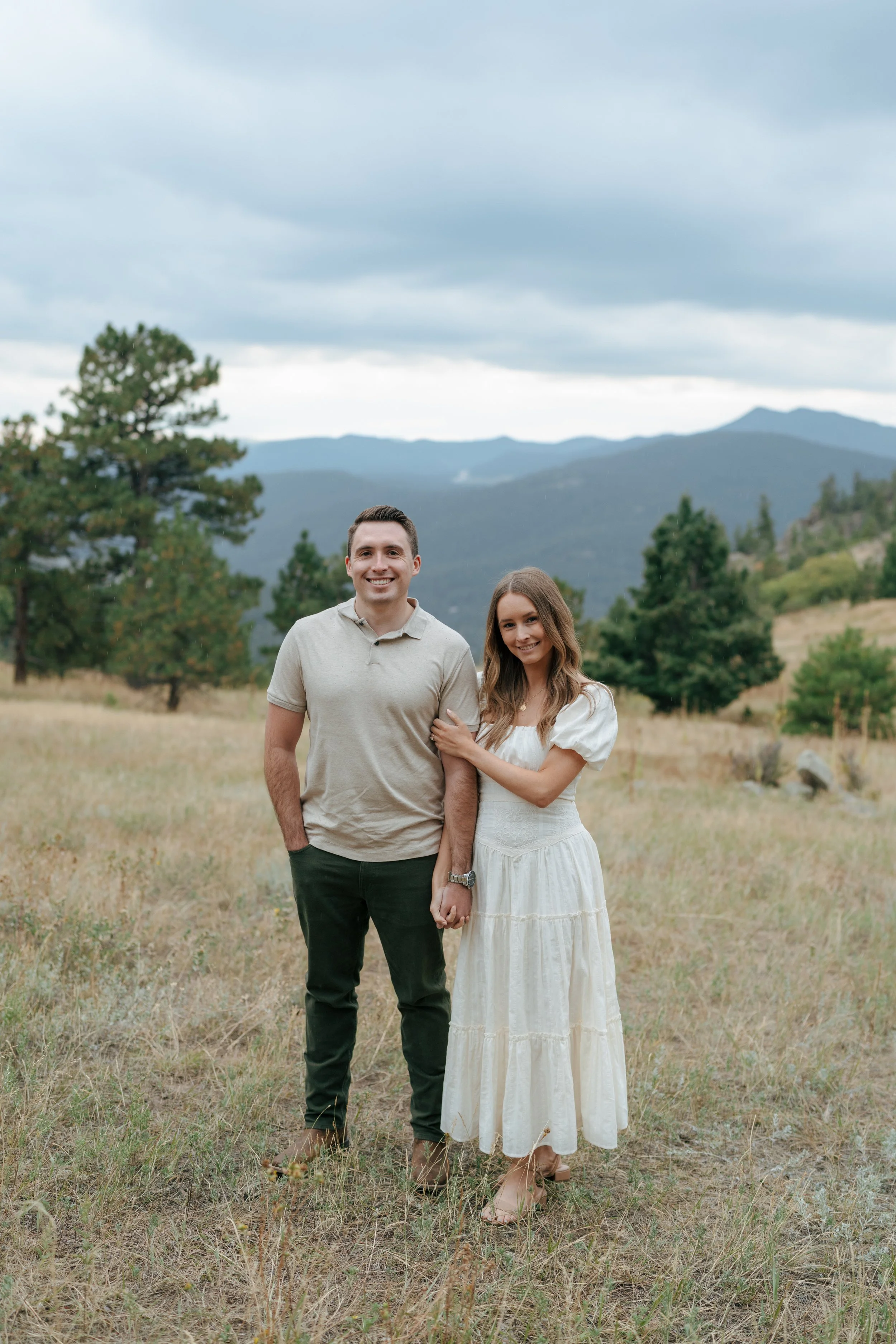 a couple standing in front of rolling mountains for their engagement photoshoot