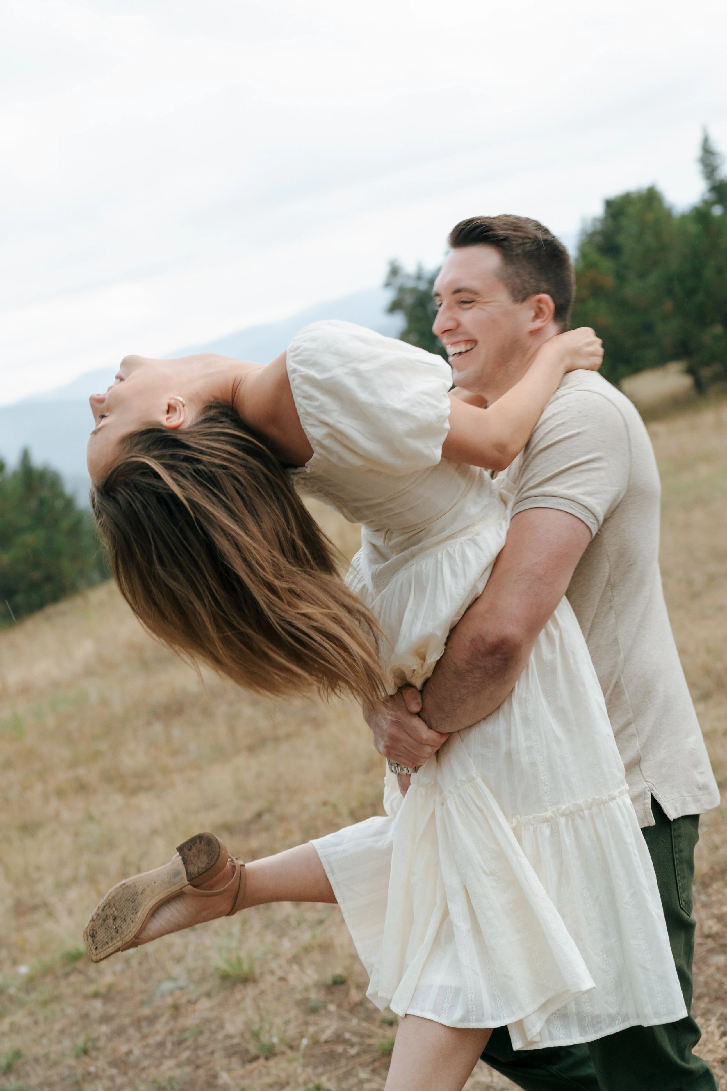 a man holding up a woman as she does a backbend during an engagement photoshoot