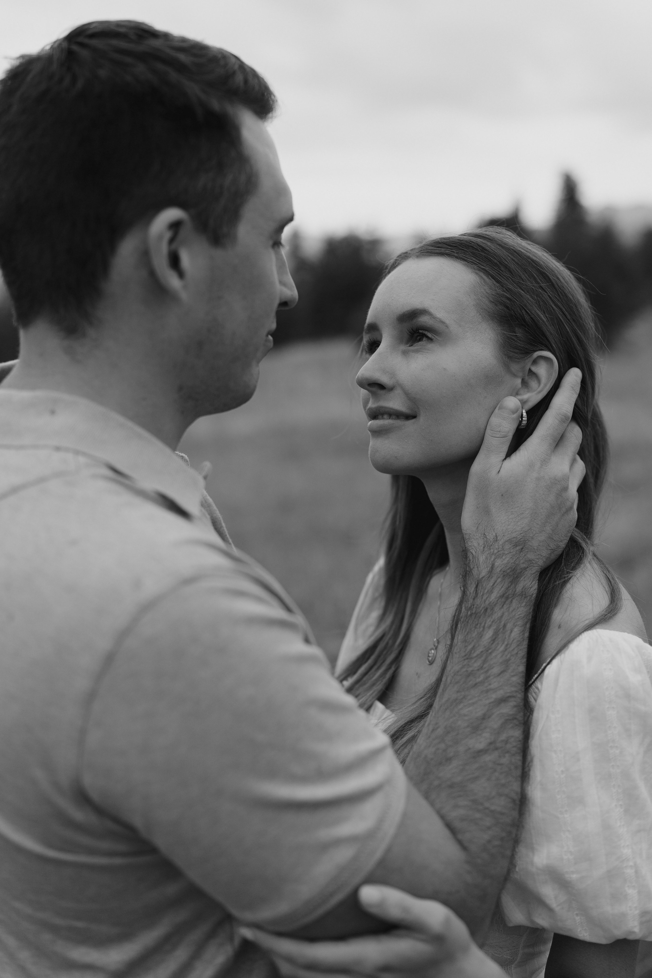 a man pushing back a woman's hair behind her ears during engagement photoshoot