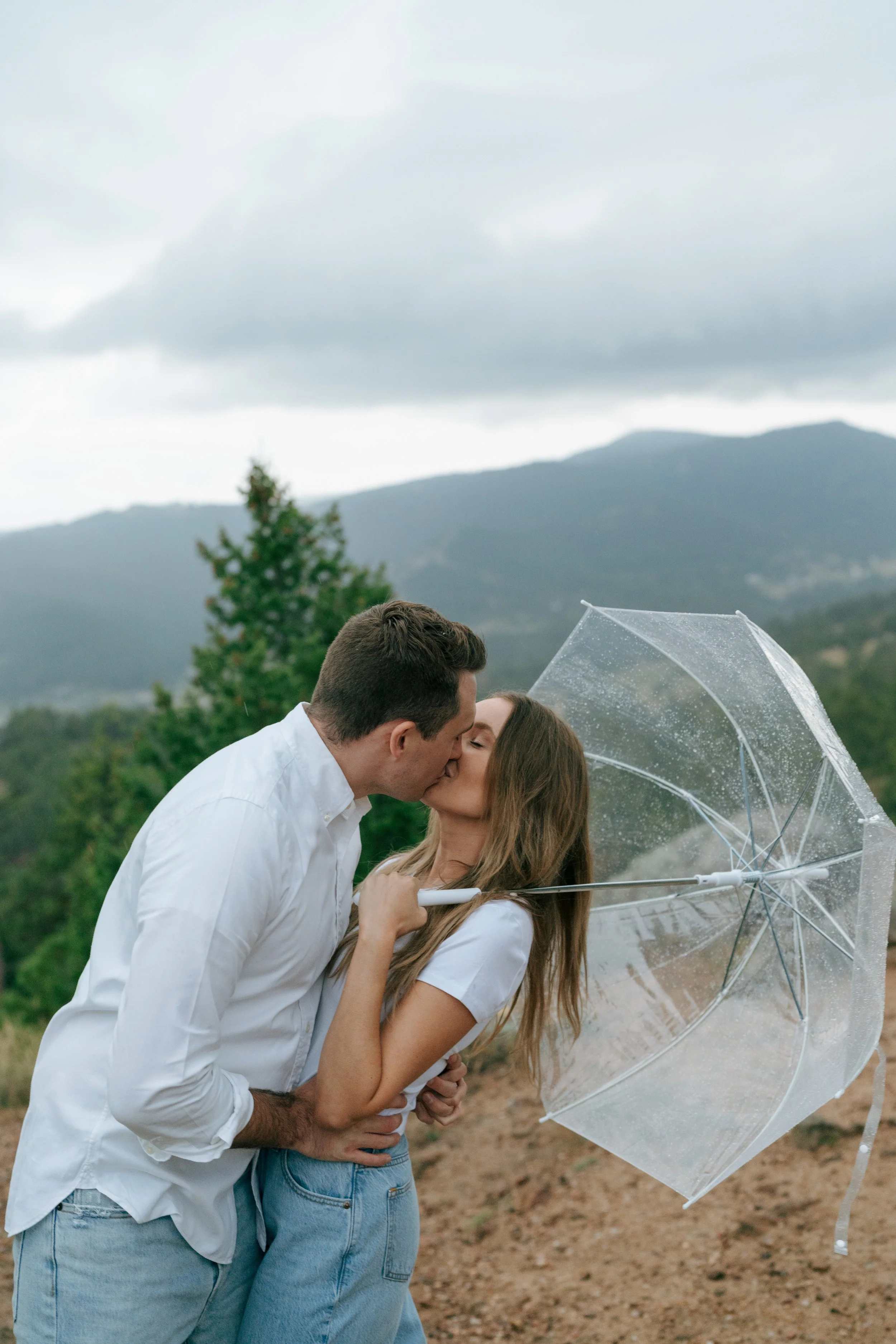 a couple kissing in the rain during their engagement photoshoot in CO