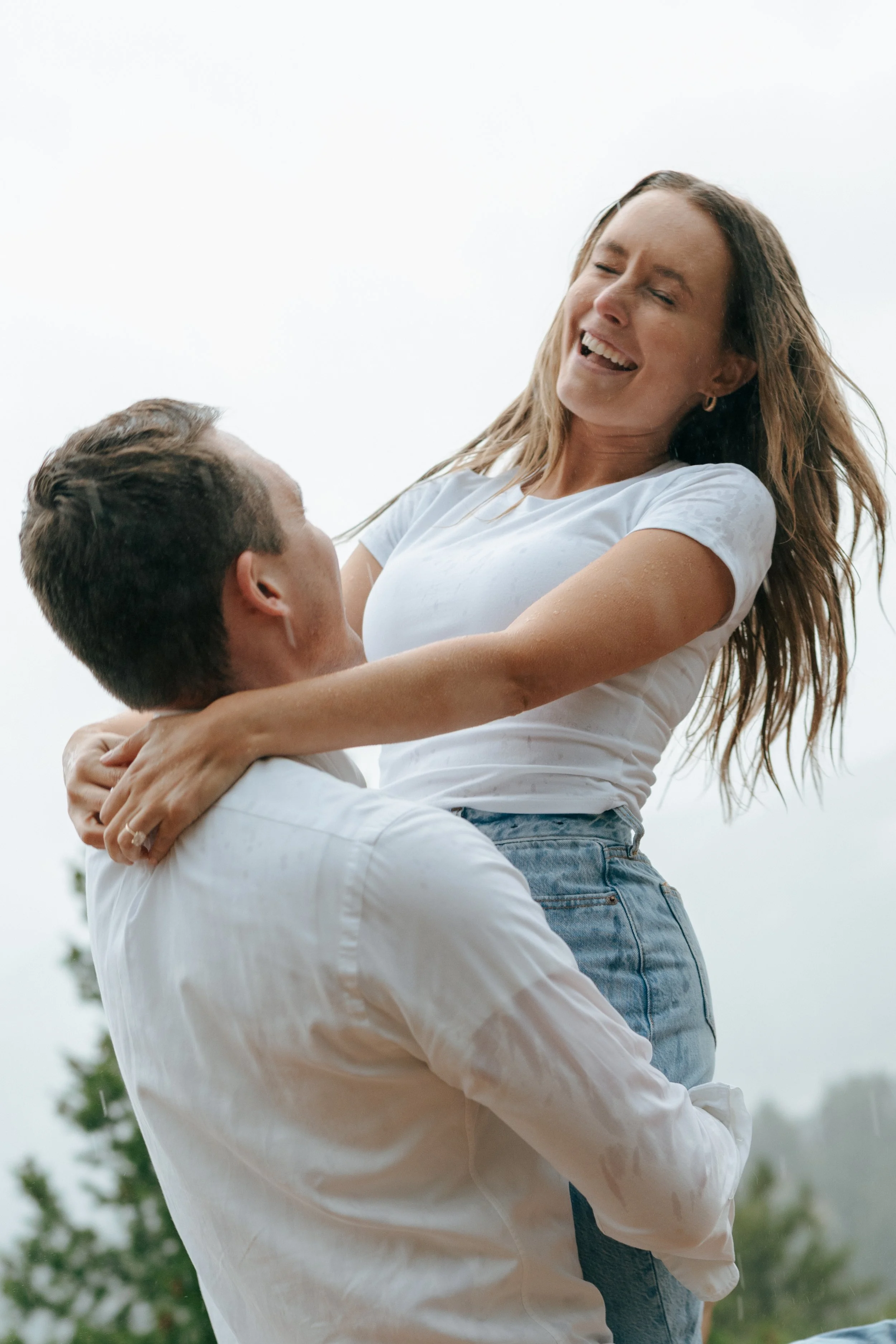 a man holding a woman in the rain during a engagement photoshoot