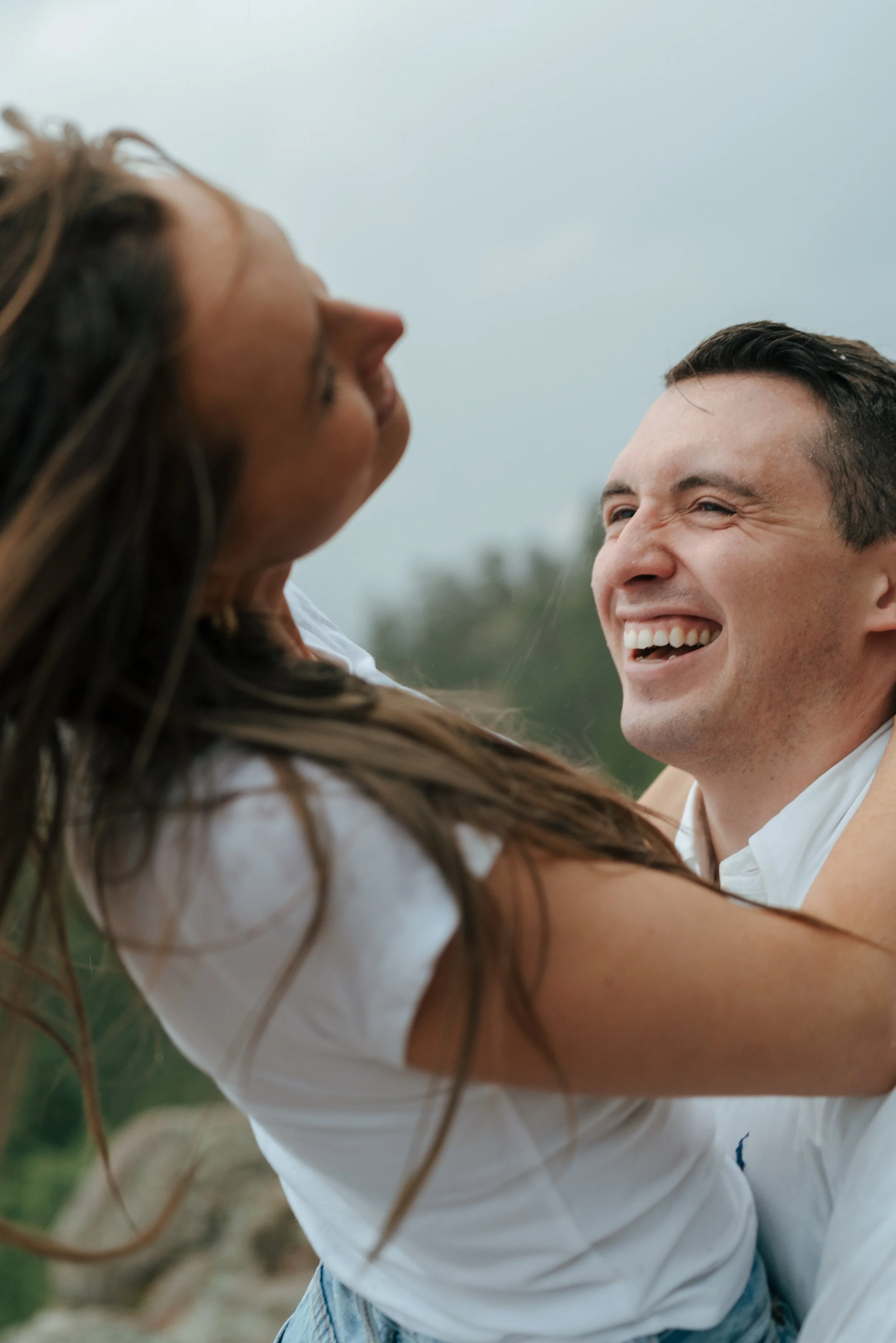 a man laughing as he looks at his fiance during their engagement photoshoot
