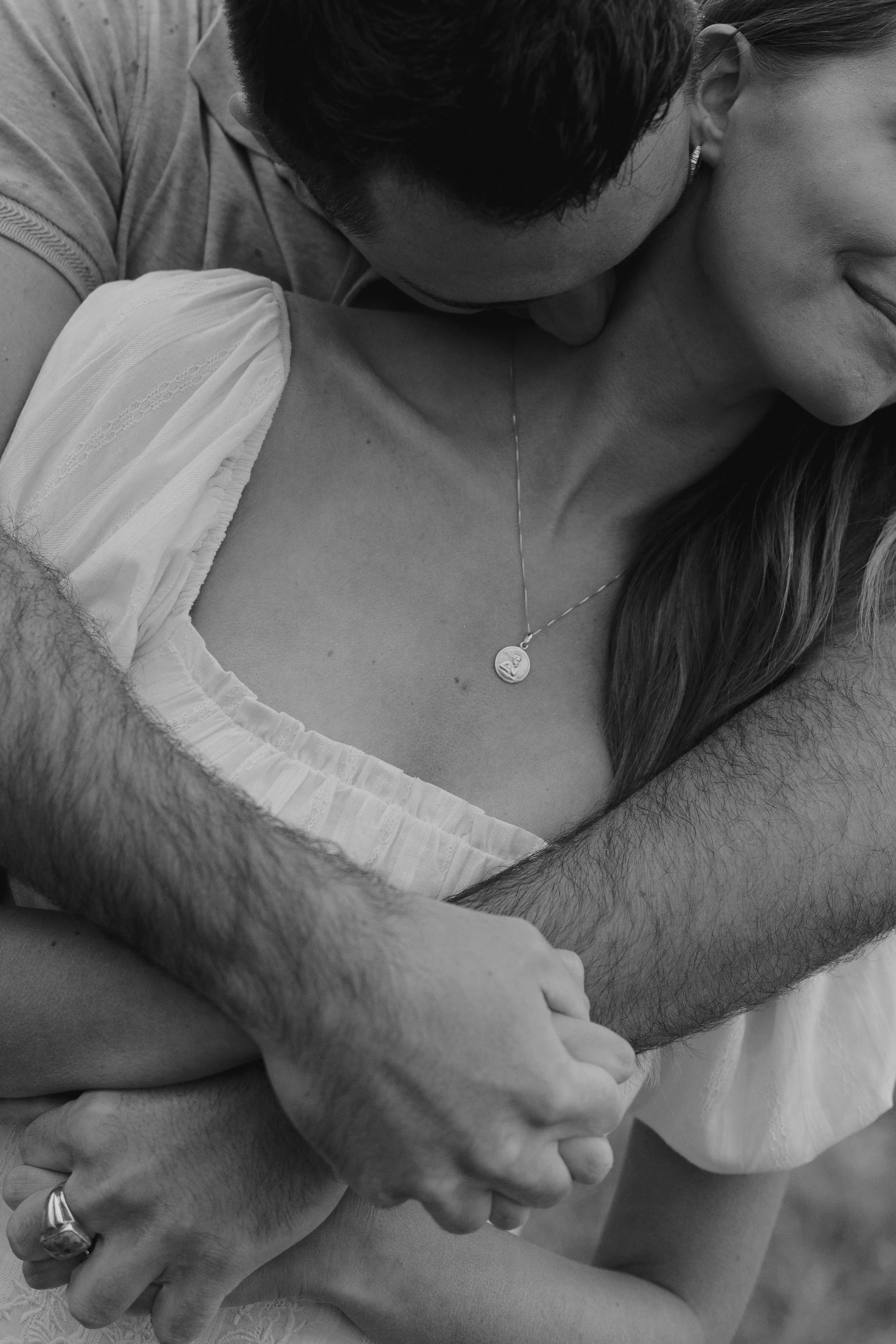 a close up of a man kissing a woman's neck during an engagement photoshoot