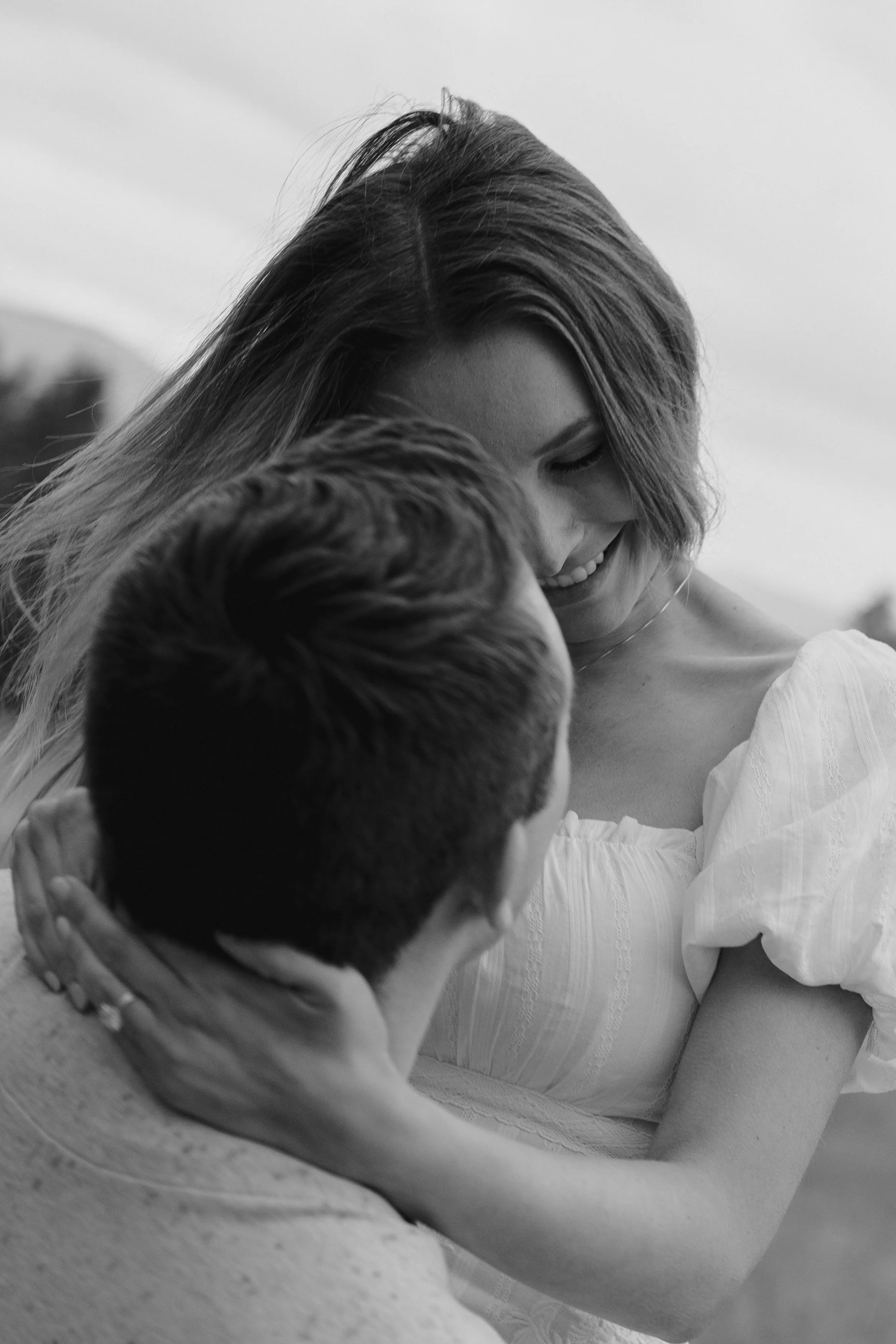 a woman looking down on a man as he holds her up 