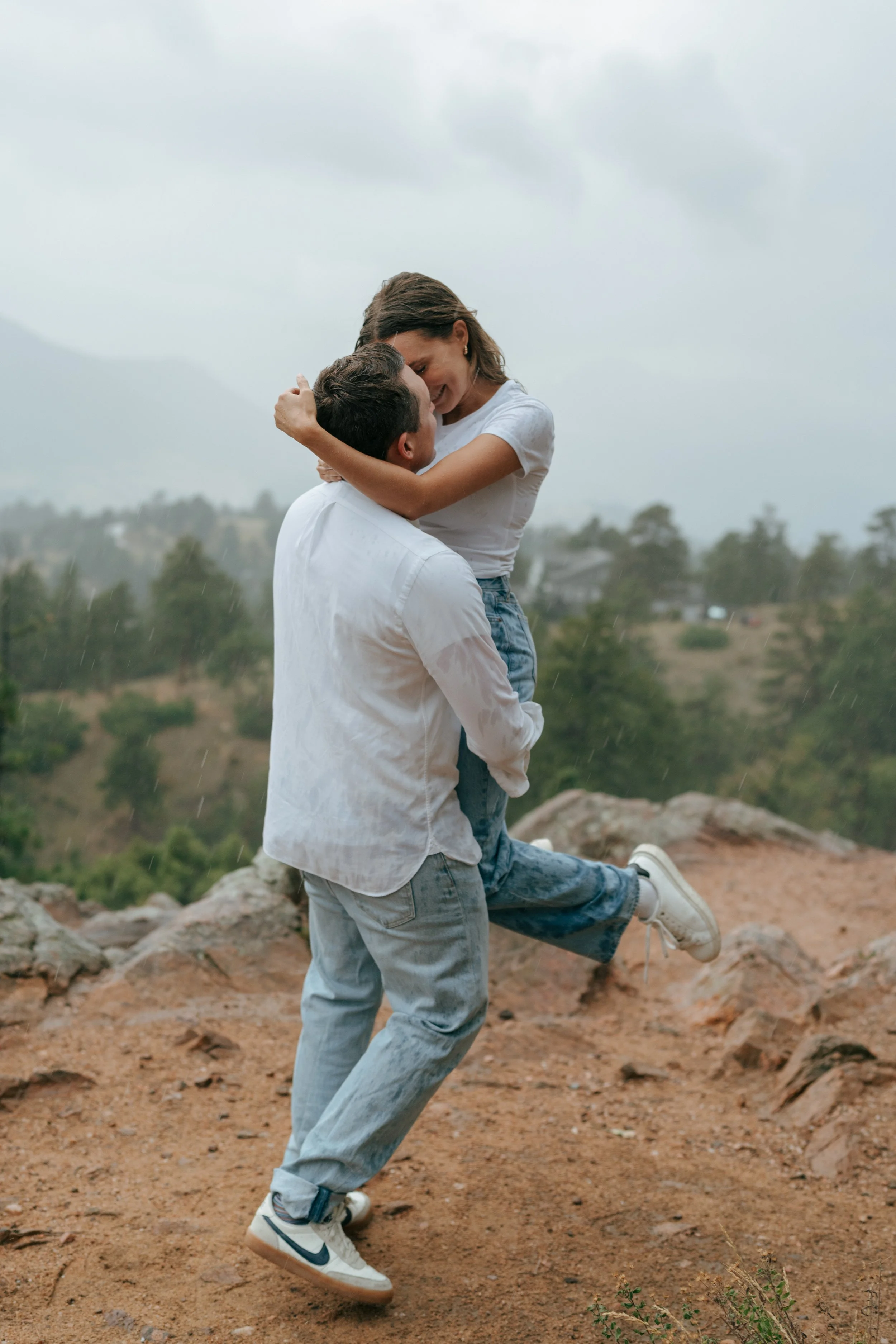 a couple kissing in the rain during an engagement photoshoot