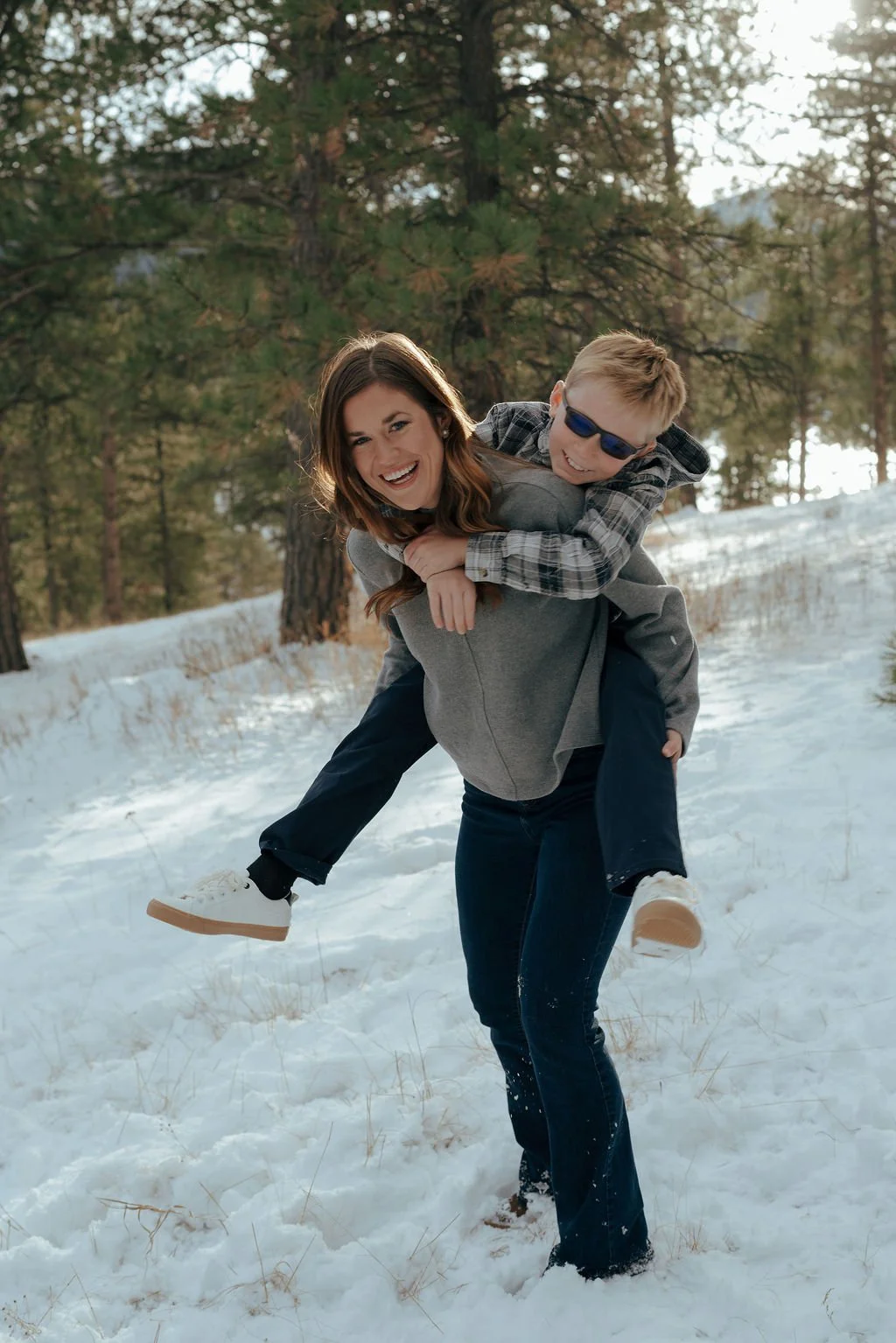 A man, woman, child, and a golden retriever stand together in a snowy forest with pine trees in the background for a documentary family photography session