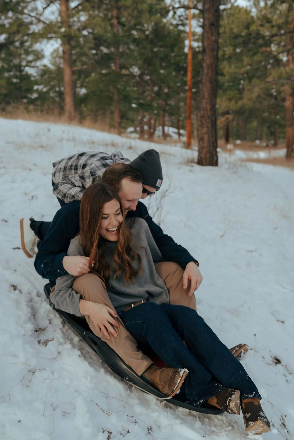 A man, woman, child, and a golden retriever stand together in a snowy forest with pine trees in the background for a documentary family photography session