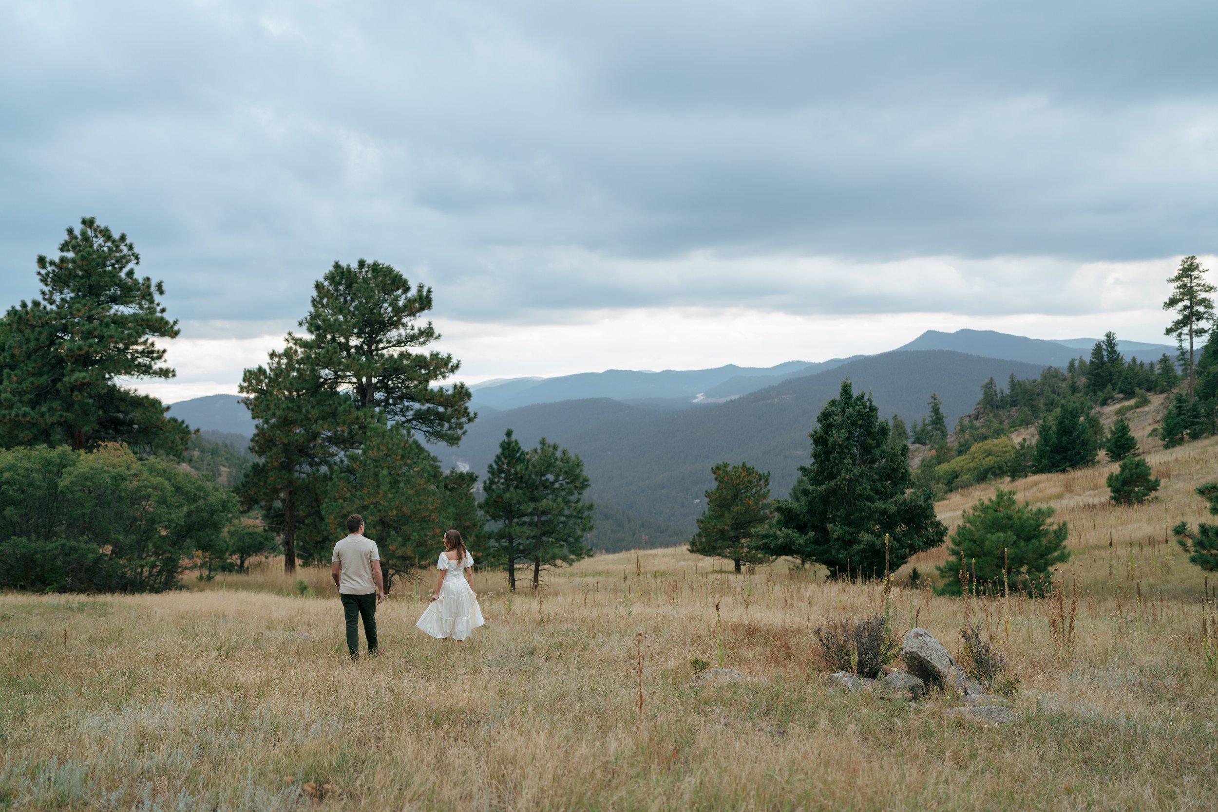 newly engaged couple walking through the grass in CO during their engagement photoshoot