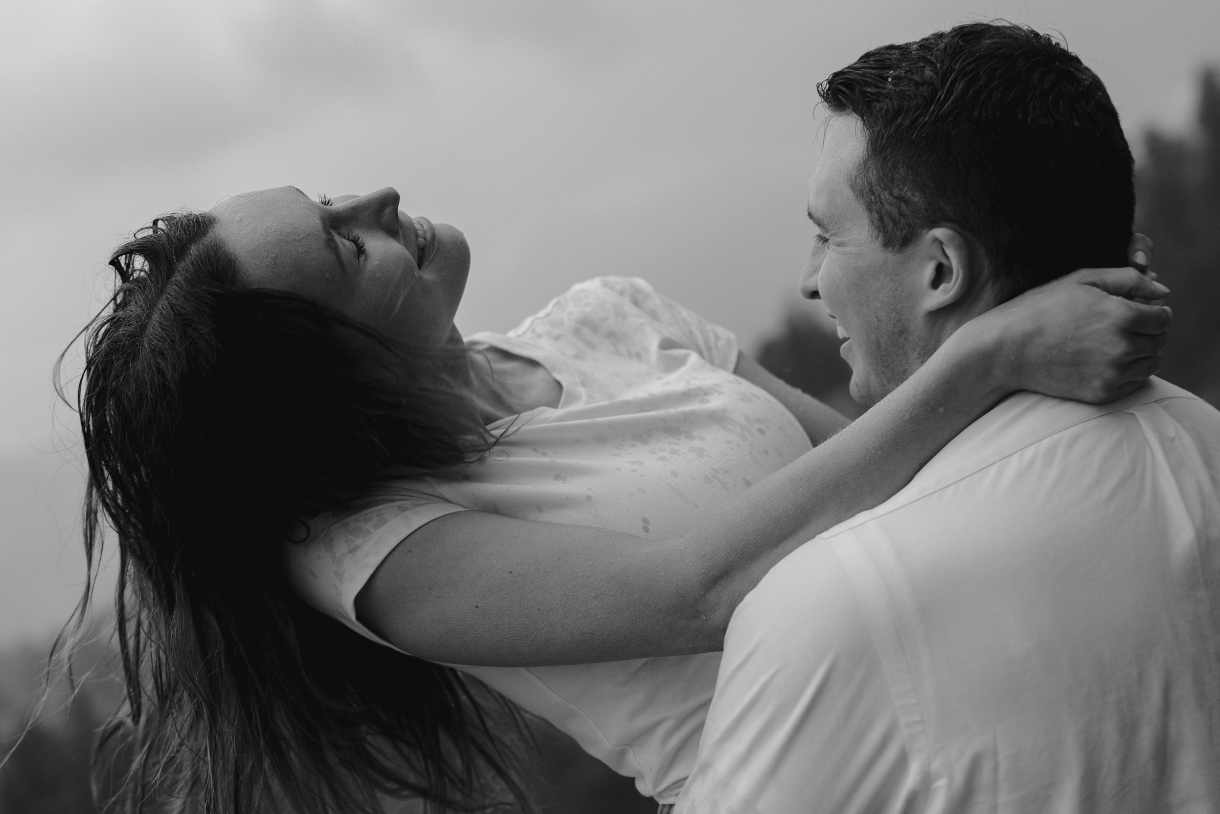 a couple smiling together in the rain during their cinematic engagement photoshoot