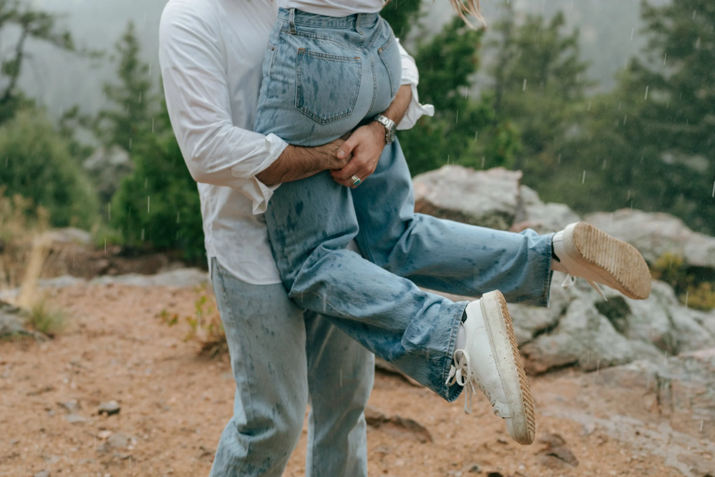 a man holding up a woman during their cinematic engagement photoshoot in the rain
