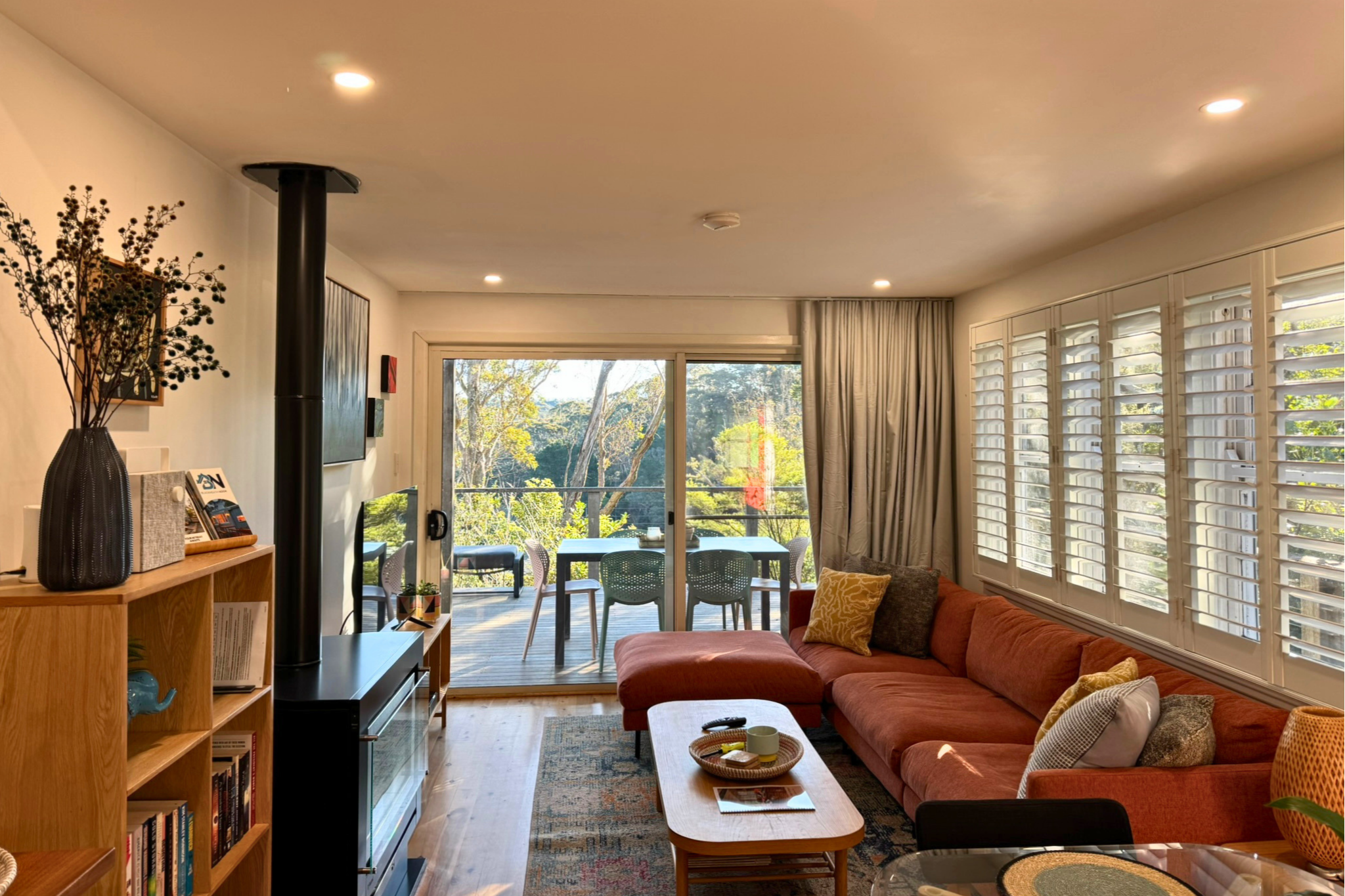 Spacious open-plan living and dining area in Katoomba accommodation with fireplace, Smart TV and balcony overlooking bushland.
