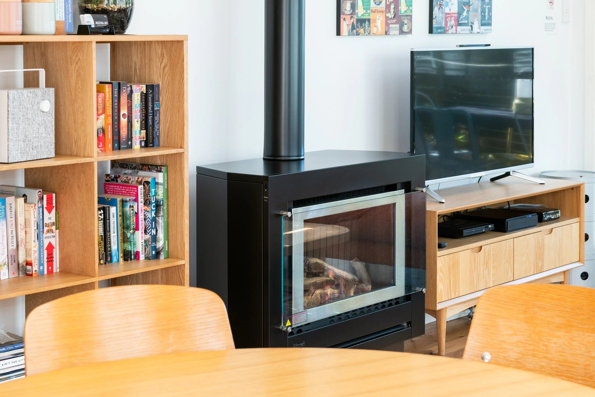 Warm and inviting living area in Blue Mountains holiday home with fireplace, bookshelves and relaxed modern styling.