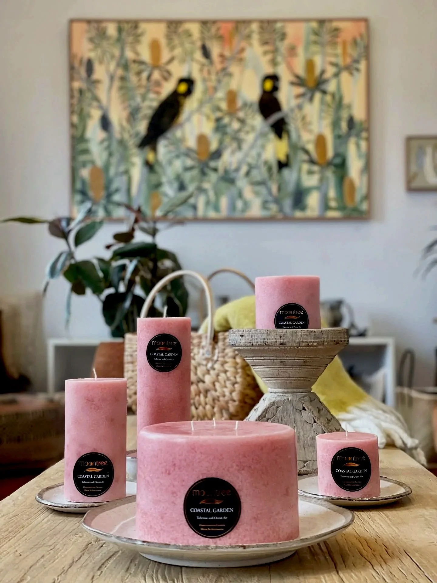 Pink Moontree scented candles displayed on a wooden table in a cosy living room setting